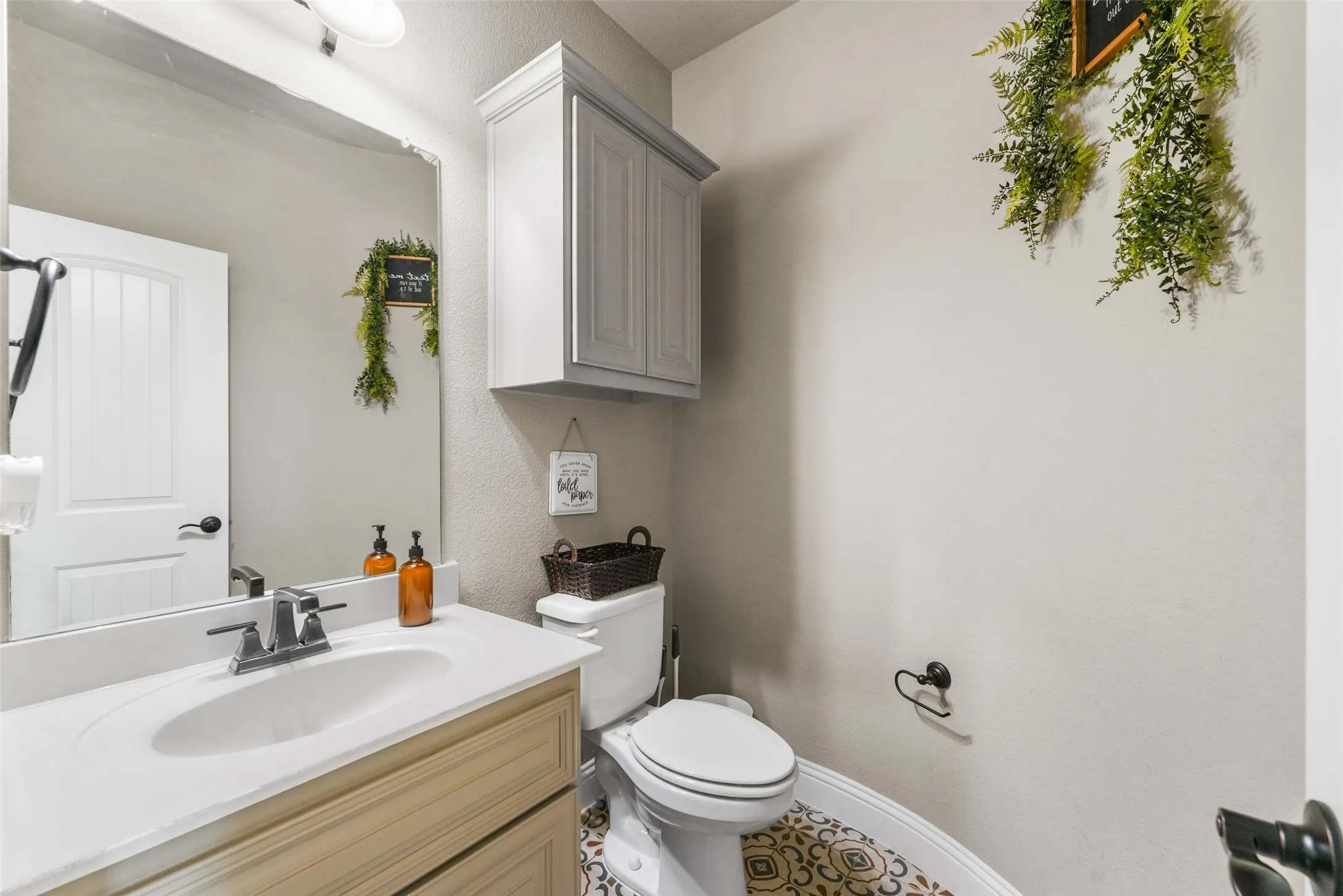Vanity with integrated sink, wall-mounted cabinetry, white panel door, and patterned floor tile