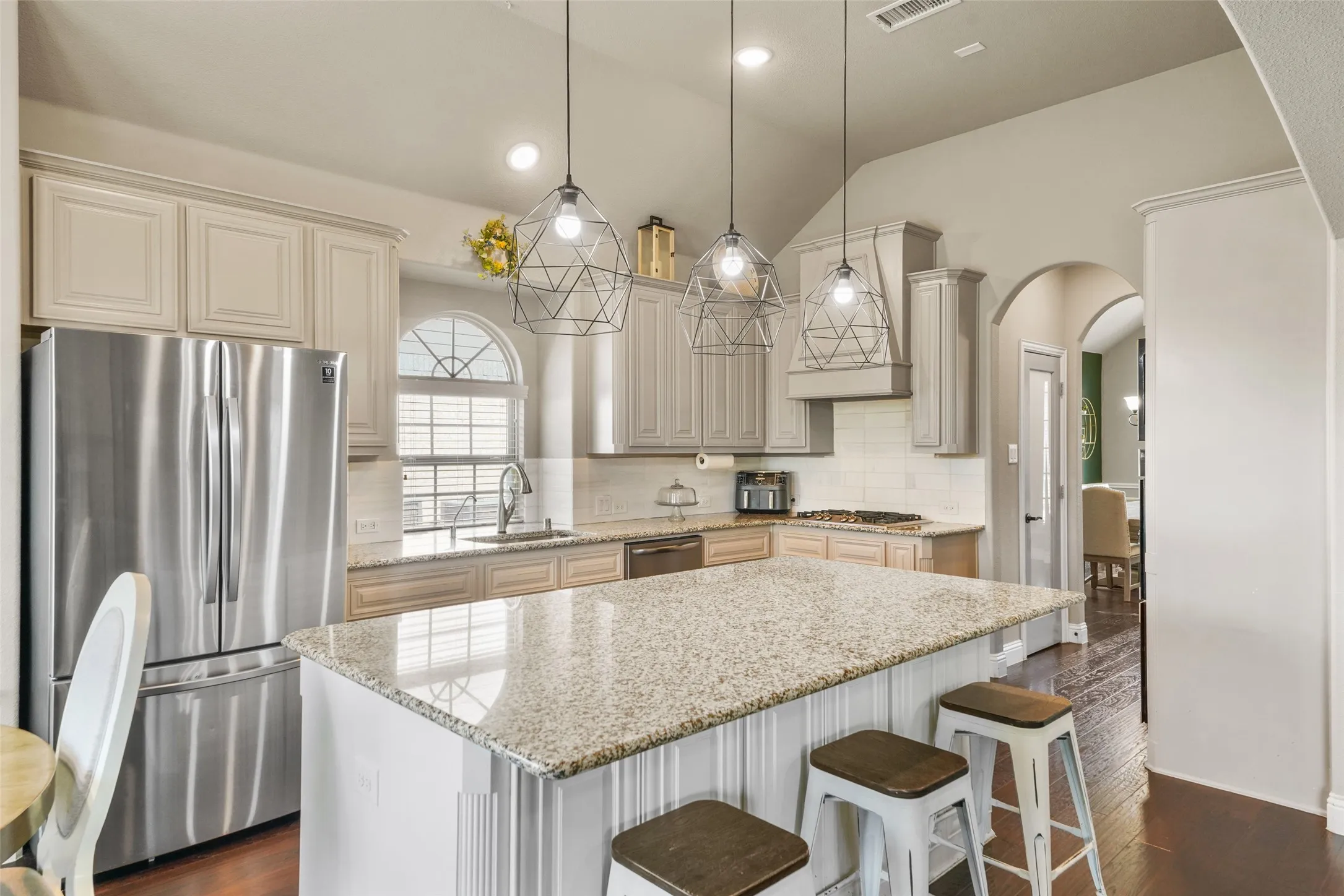 Gourmet kitchen featuring a large island with granite countertop, stainless steel appliances, white subway tile backsplash, and decorative pendant lighting