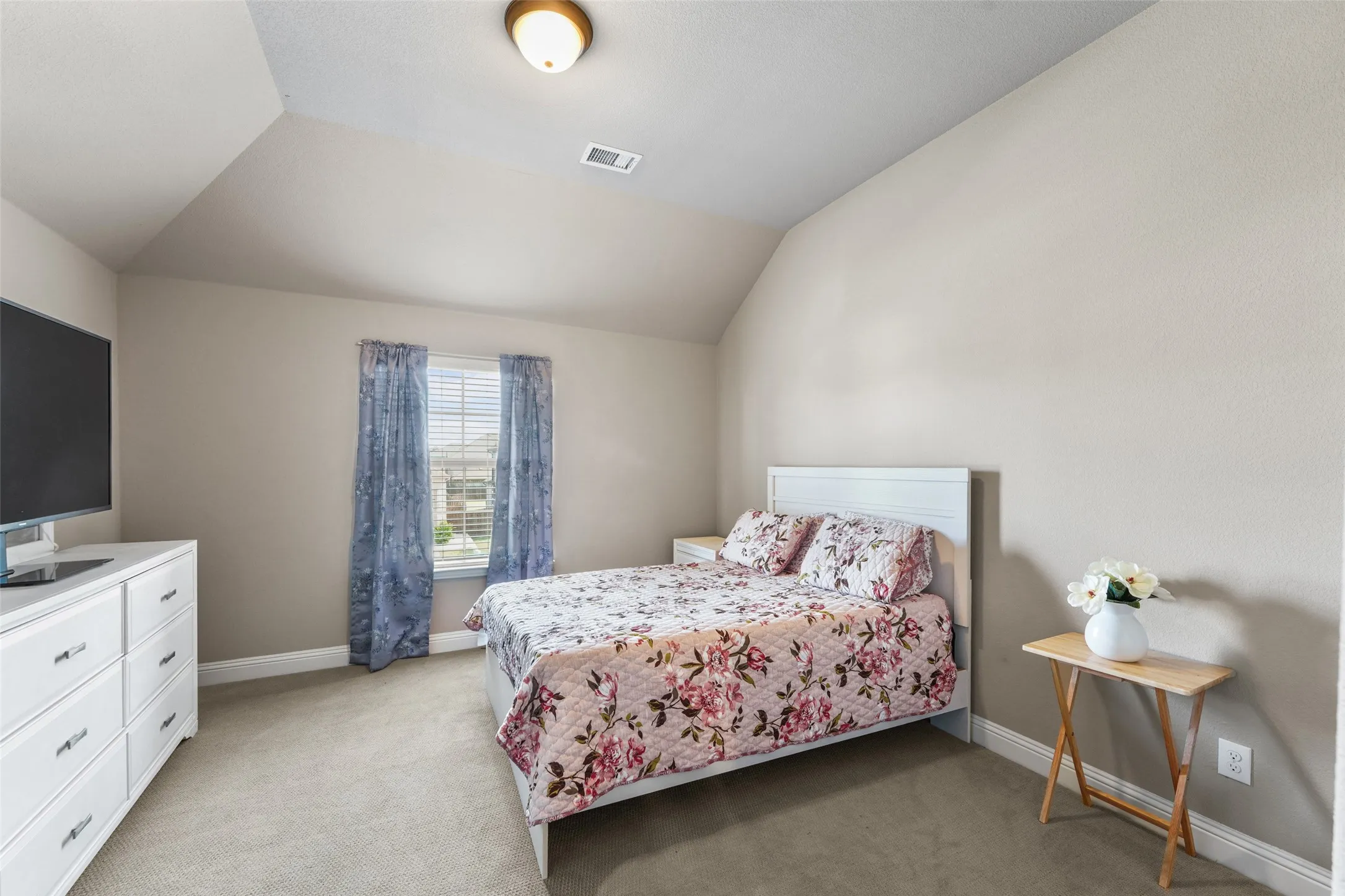 Carpeted room with a vaulted ceiling, single window, and a flush-mount overhead light fixture