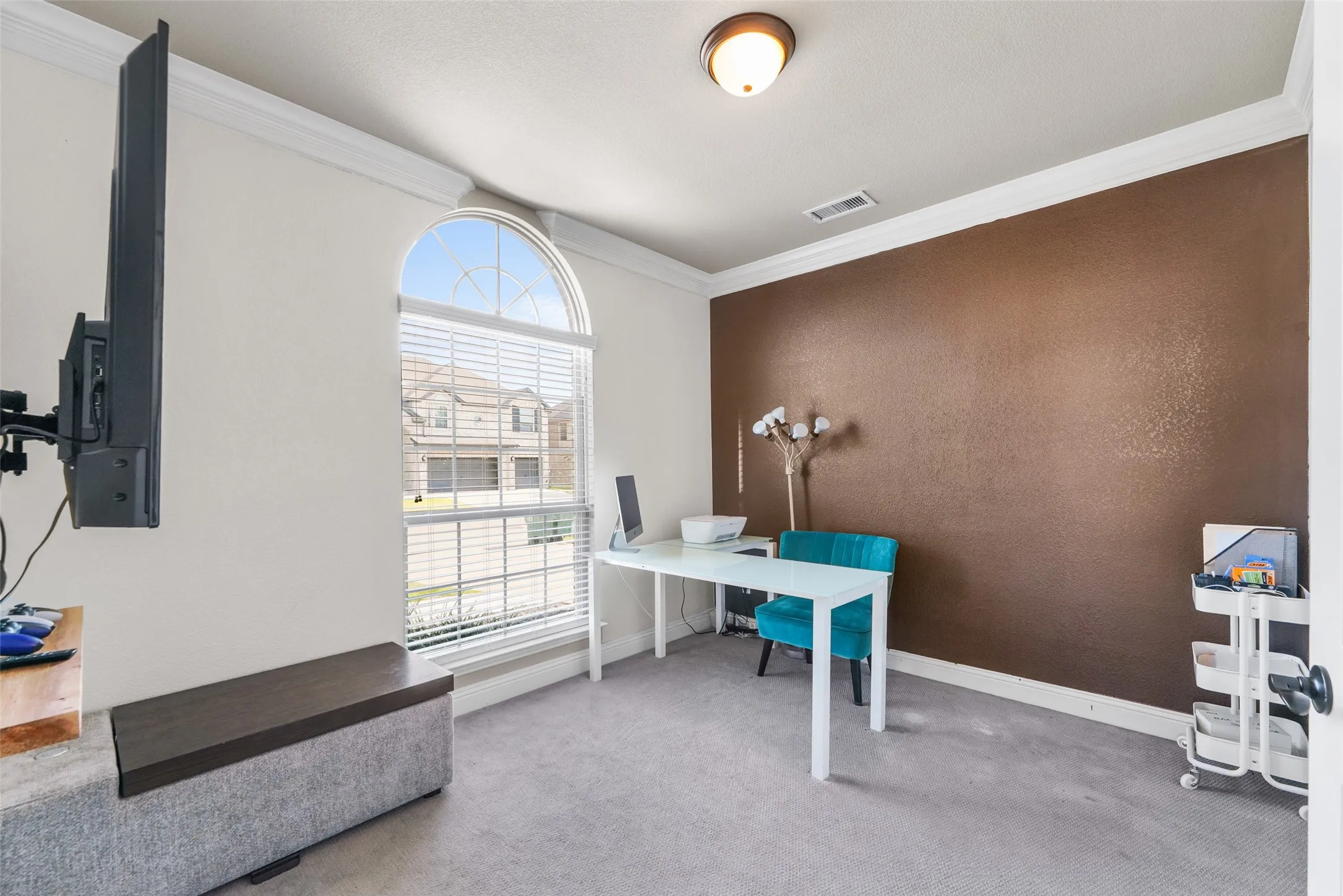 Arched window with blinds, crown molding, a textured accent wall, and recessed ceiling light