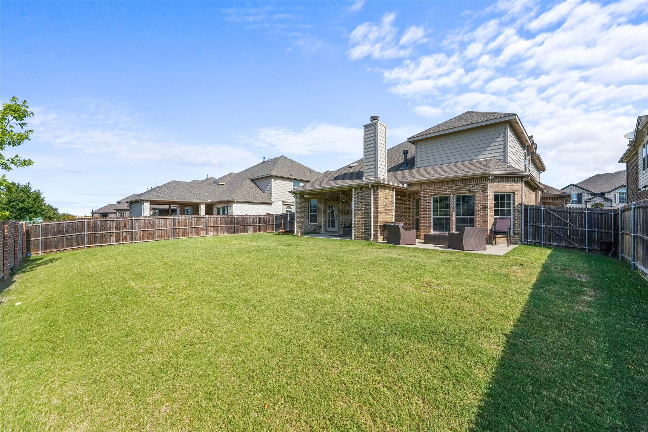 Expansive backyard featuring a manicured lawn, full wood fencing, and a concrete patio