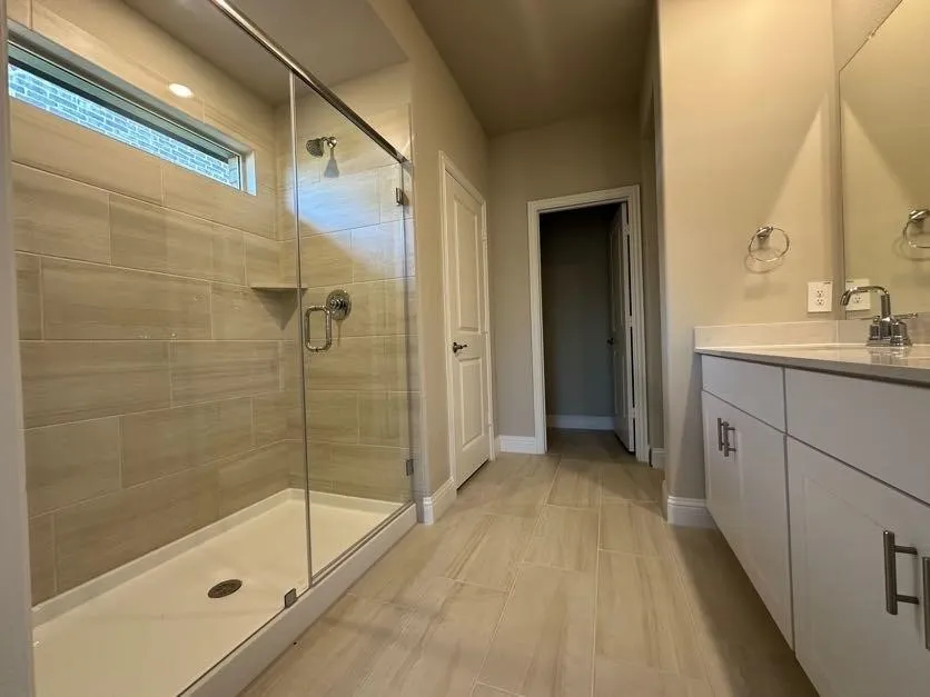 Spacious bathroom featuring a glass-enclosed shower with tile surround, a built-in shower niche, and a transom window