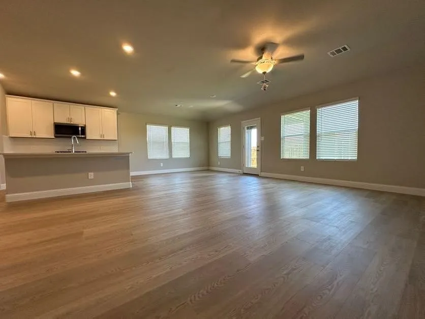 Open-concept living area featuring wood-finish flooring, recessed lighting, and a ceiling fan