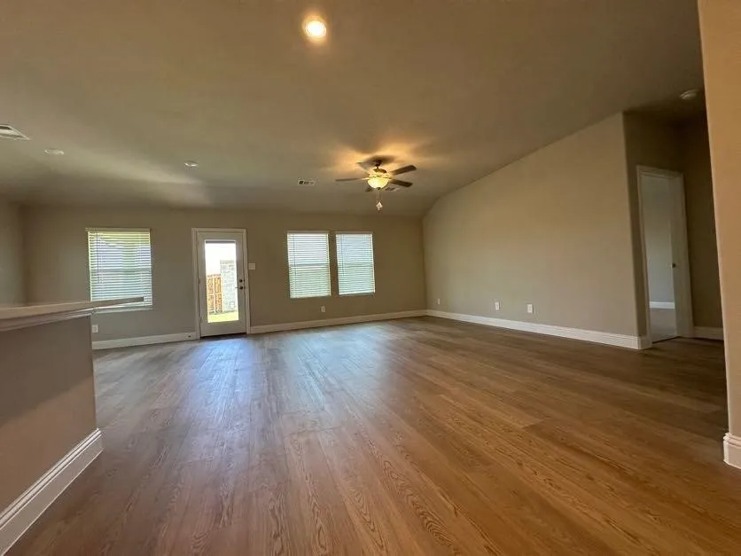 Spacious living area featuring wood-finish flooring, recessed lighting, and a ceiling fan