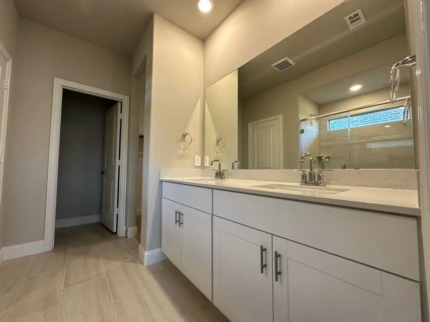 Dual vanity with white cabinetry, light-toned countertops, and chrome fixtures