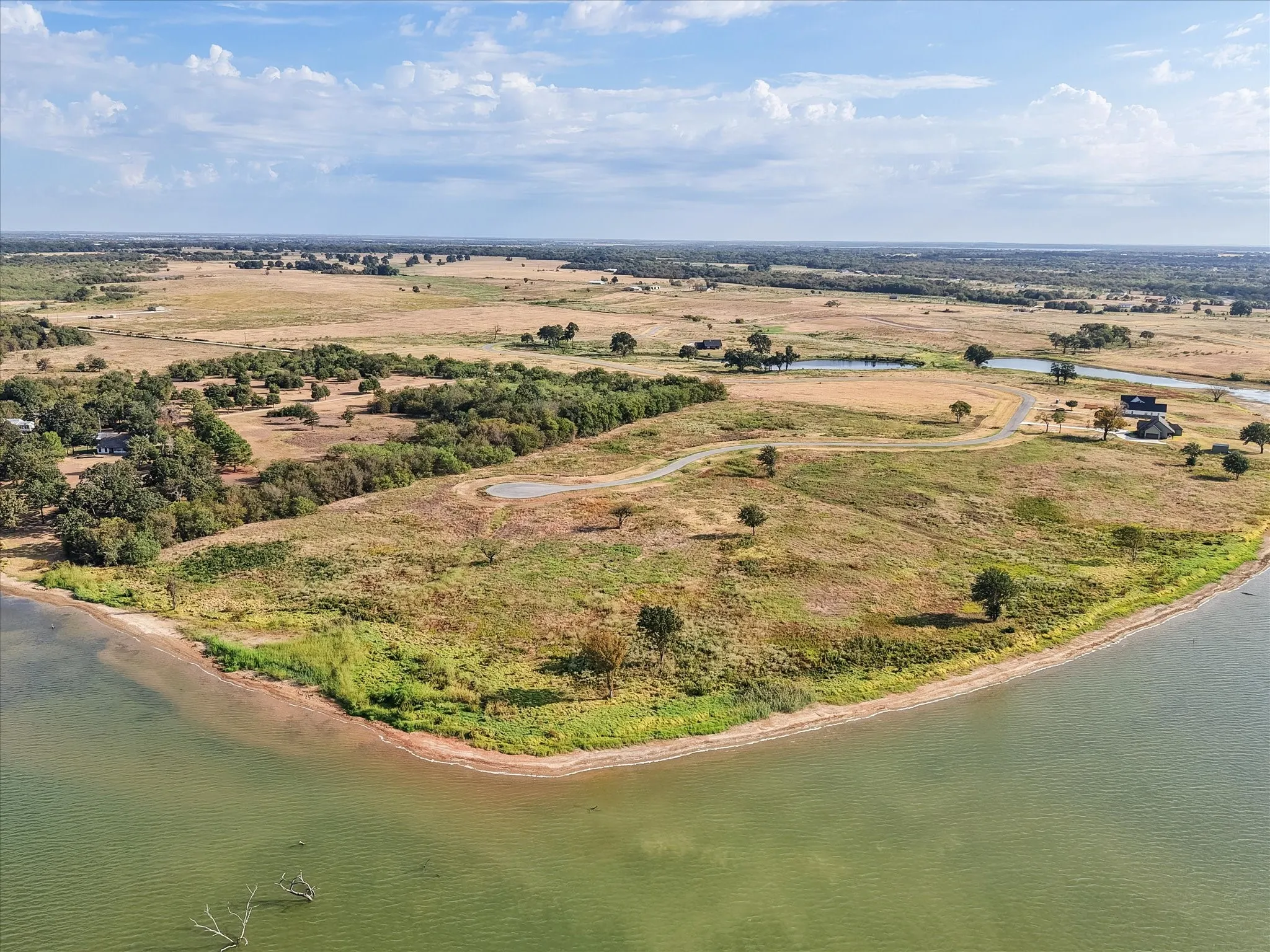 Expansive waterfront property featuring natural terrain, mature trees, and a private pond