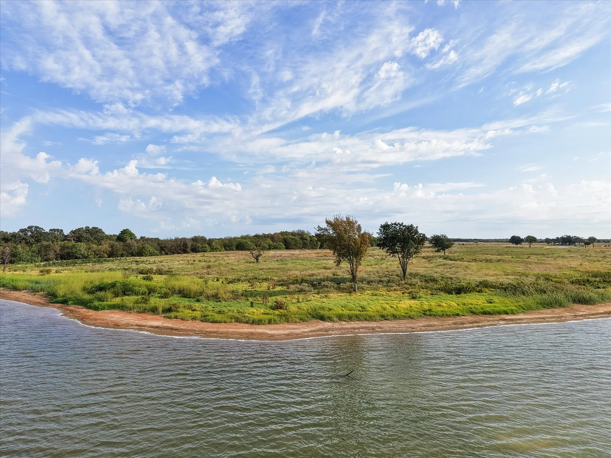Expansive waterfront acreage featuring a natural shoreline and mature trees
