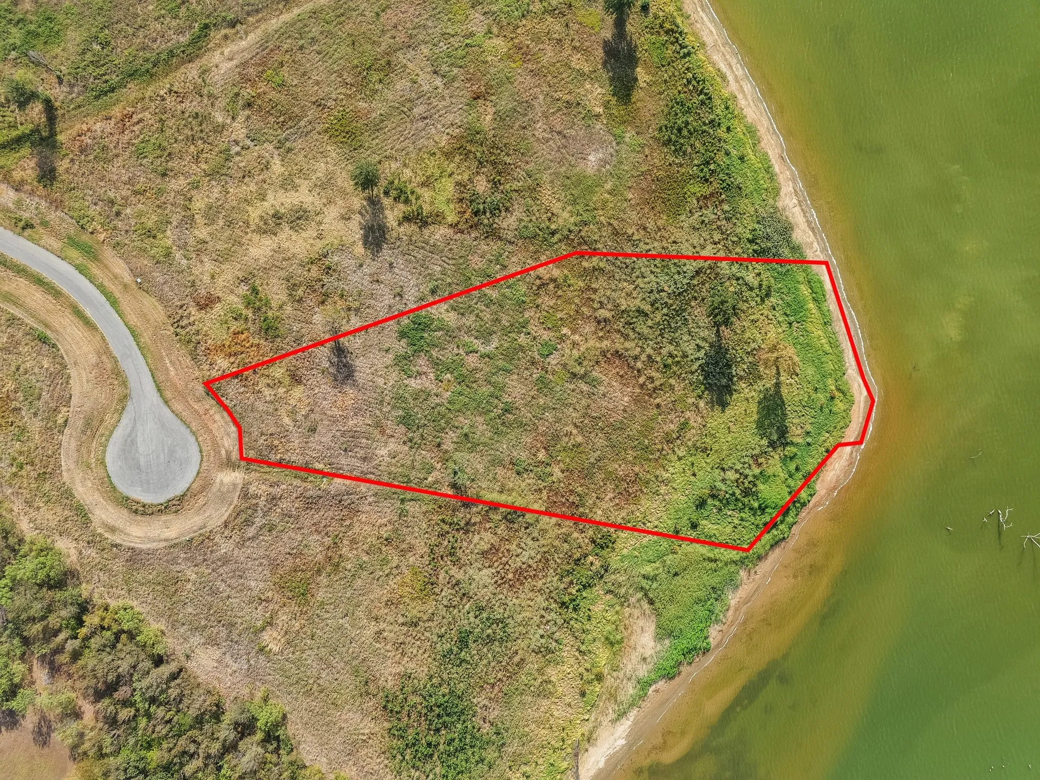 Waterfront parcel featuring direct water frontage, natural vegetation, and a cul-de-sac access
