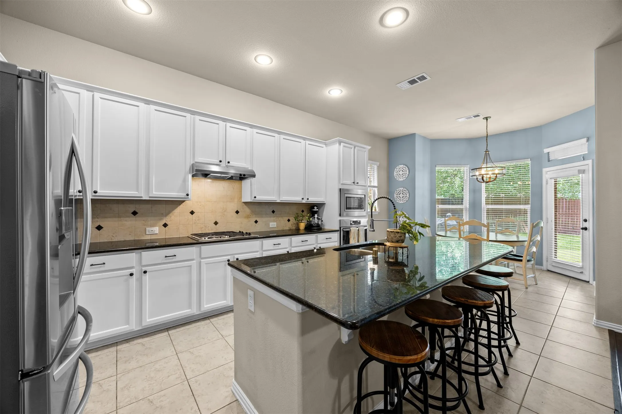 Spacious kitchen with oversized granite island, seating, gas cooktop, built-in oven and microwave, stainless steel appliances and abundant cabinetry