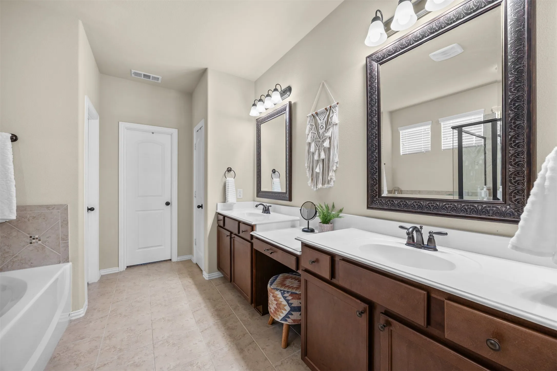 Primary bath with dual vanities, makeup vanity, soaking tub, separate walk-in shower and spacious closet.