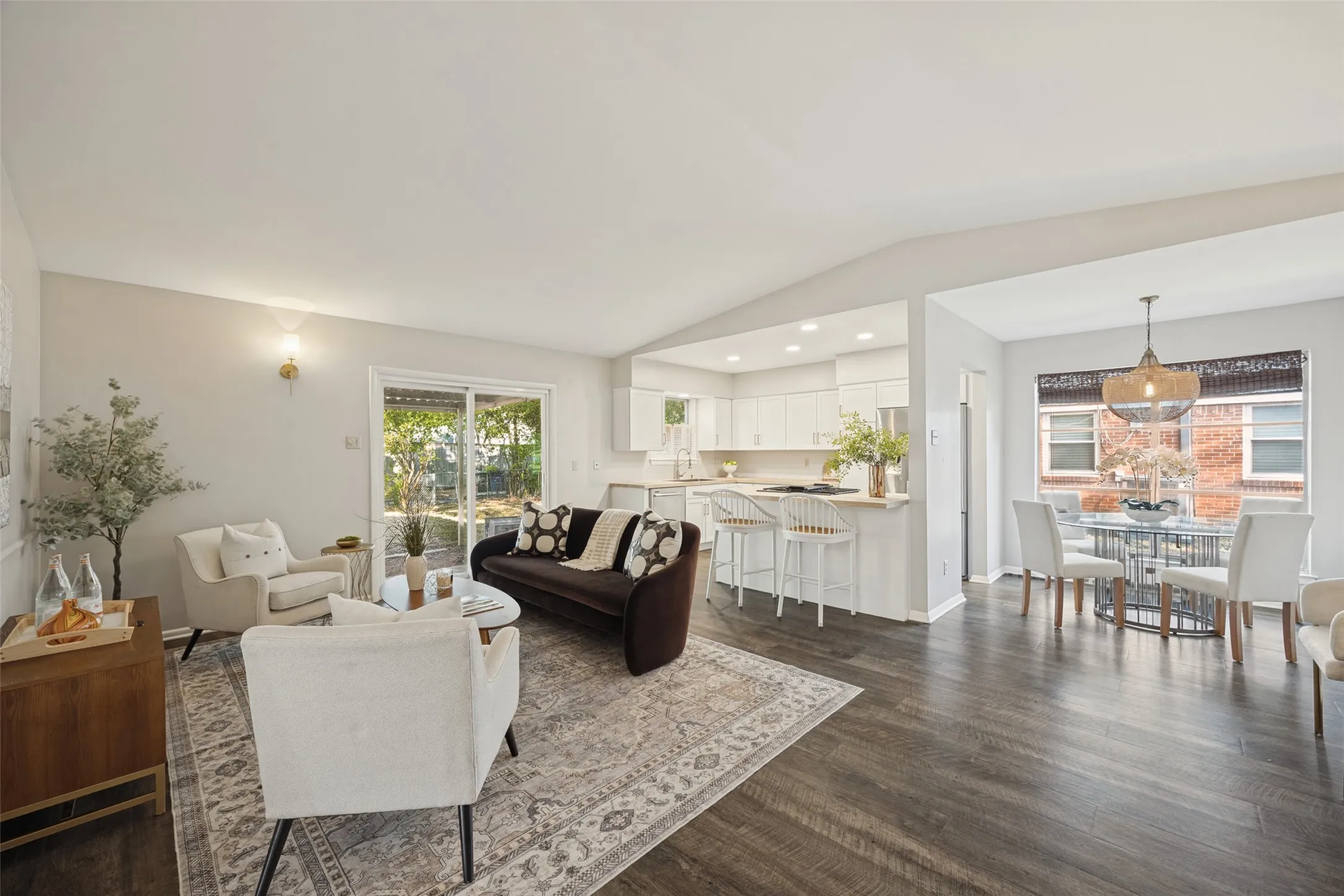 Open-concept living space featuring wood-finish flooring, recessed lighting, and a vaulted ceiling