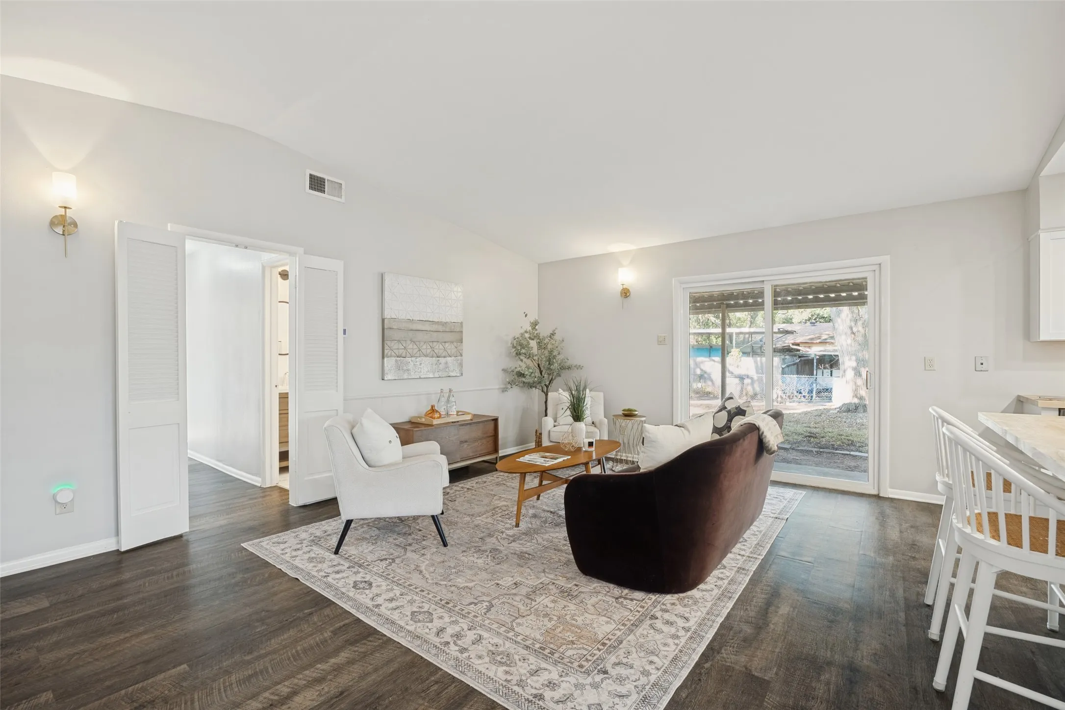 Wood-finish flooring, sliding glass door, white shaker cabinets, and wall sconces
