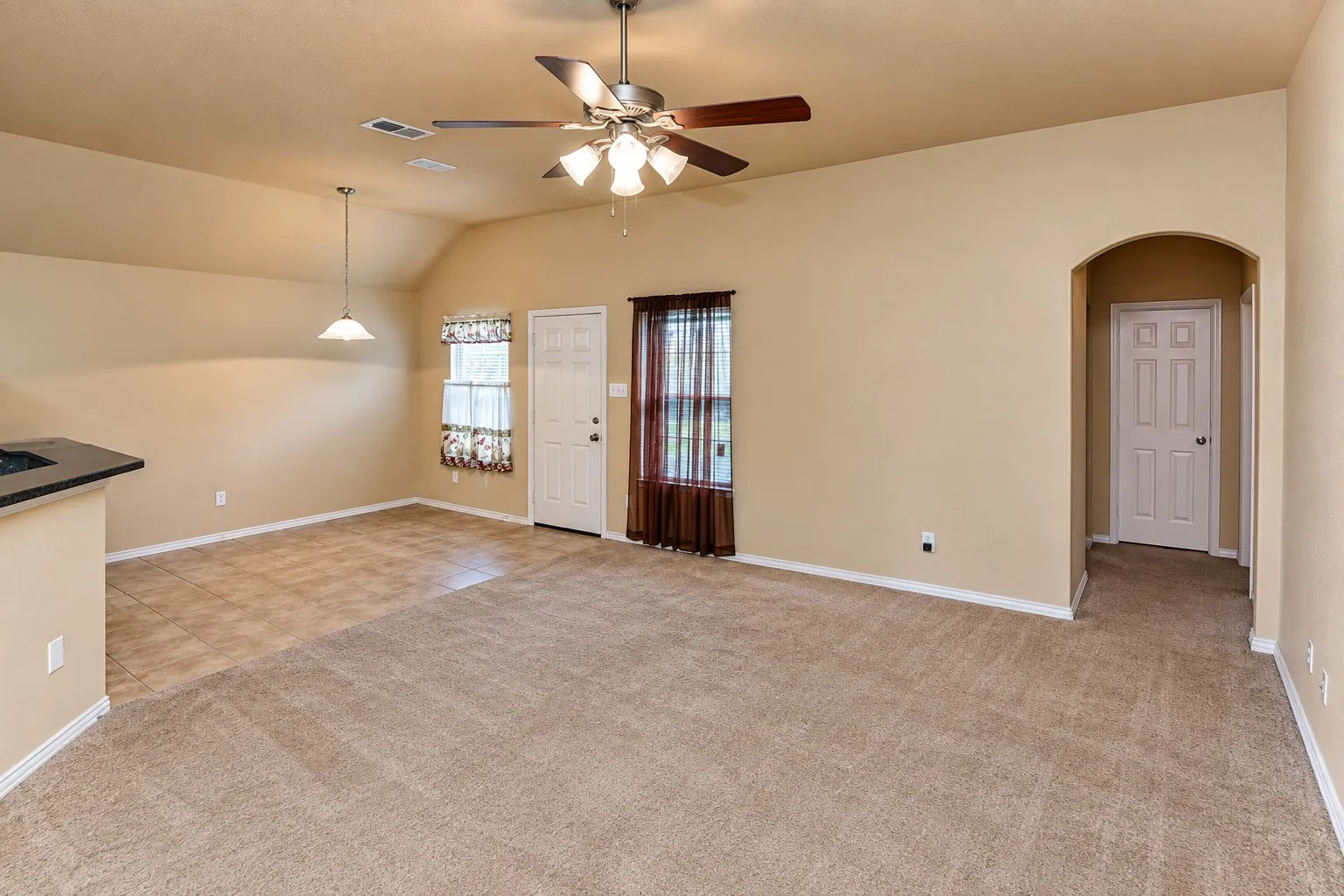 Vaulted ceiling with a ceiling fan, recessed archway, tile flooring, and a pendant light fixture