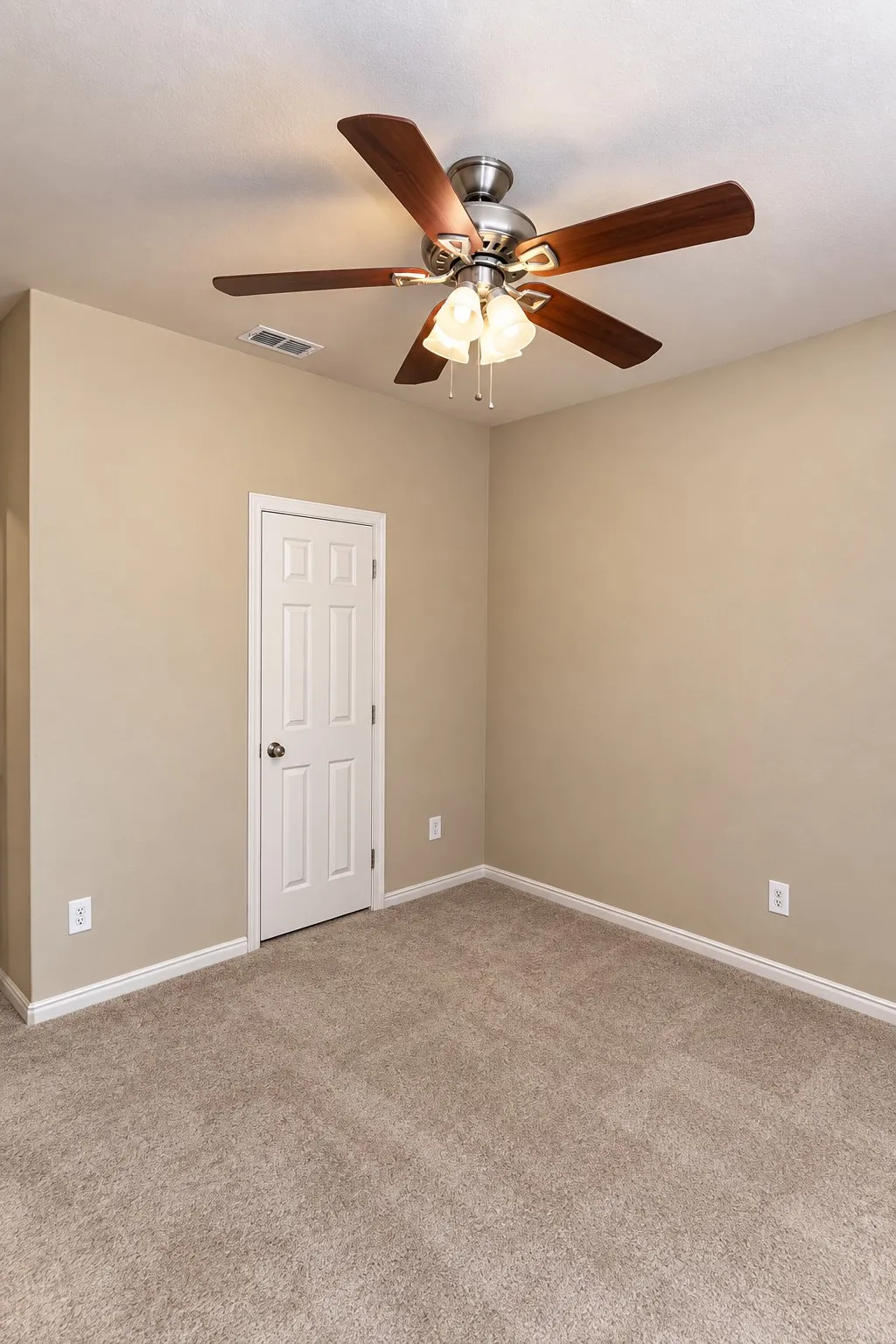 Neutral-toned wall paint, plush carpet flooring, white trim, paneled door, and a ceiling fan with integrated lighting