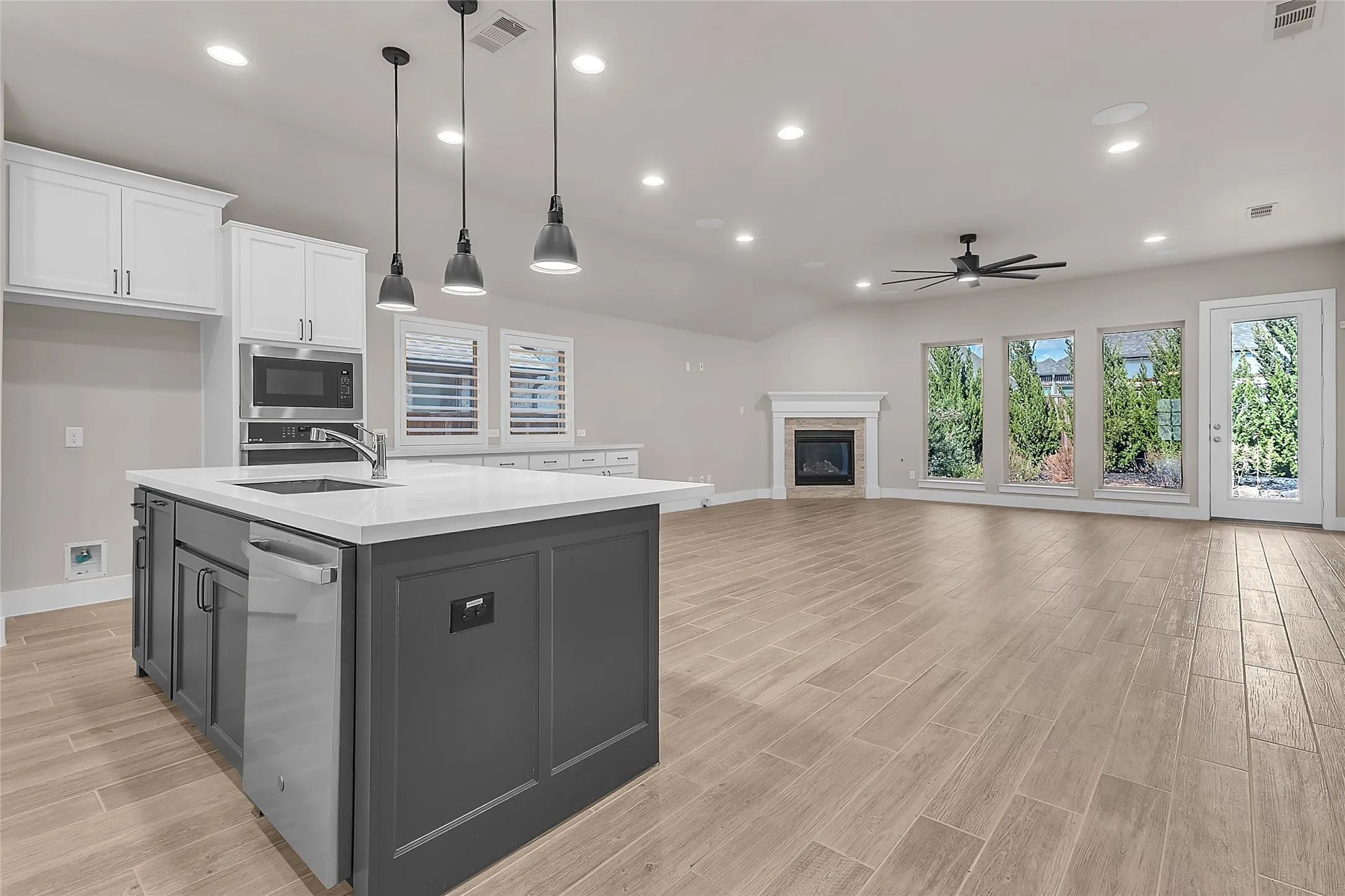Open-plan living area with hardwood flooring, recessed lighting, and a modern fireplace, enhanced by natural light from multiple large windows
