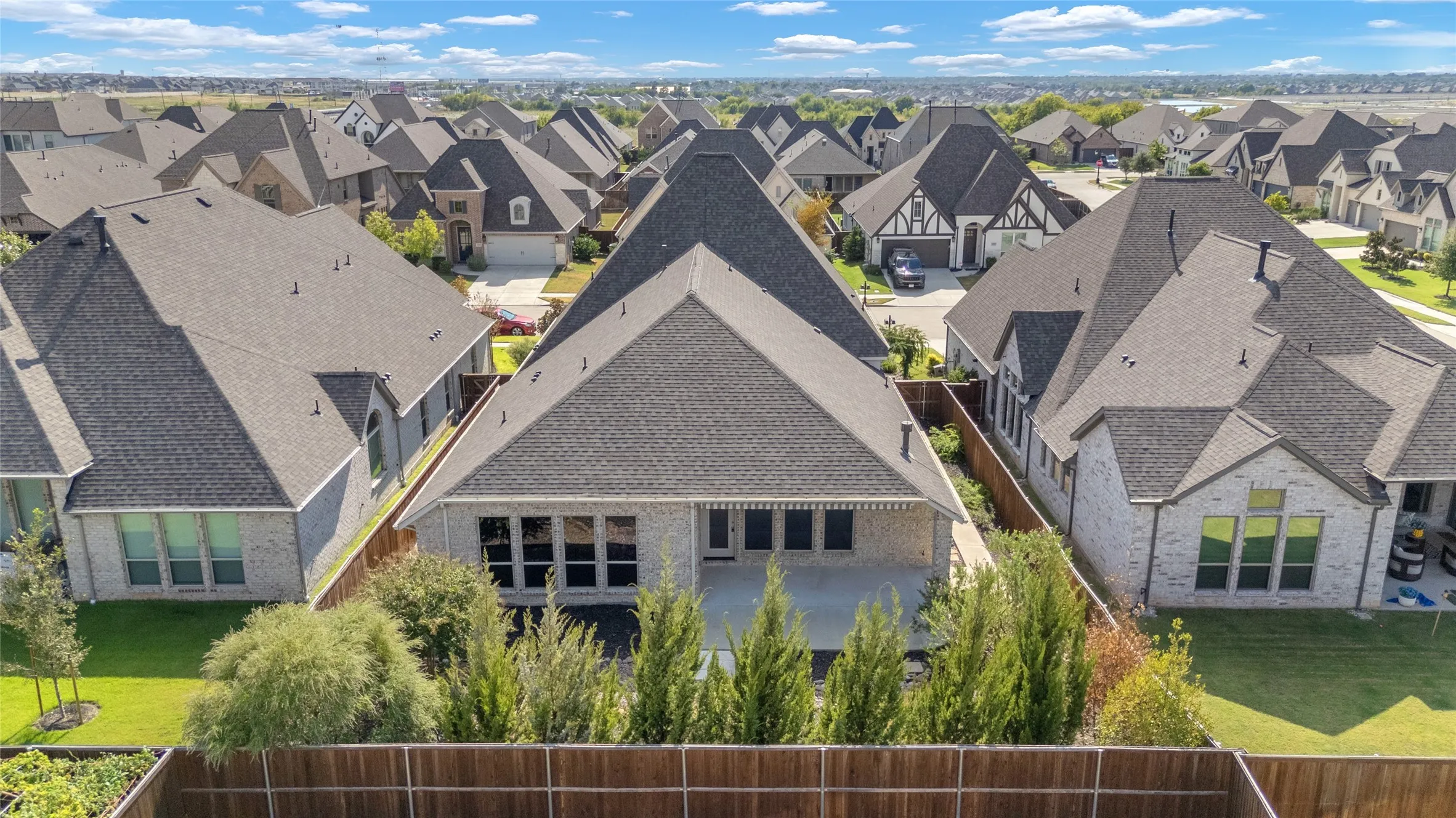 Aerial view of multiple roofs and fenced backyards showcasing various architectural styles with diagonal gables and landscaped green spaces.