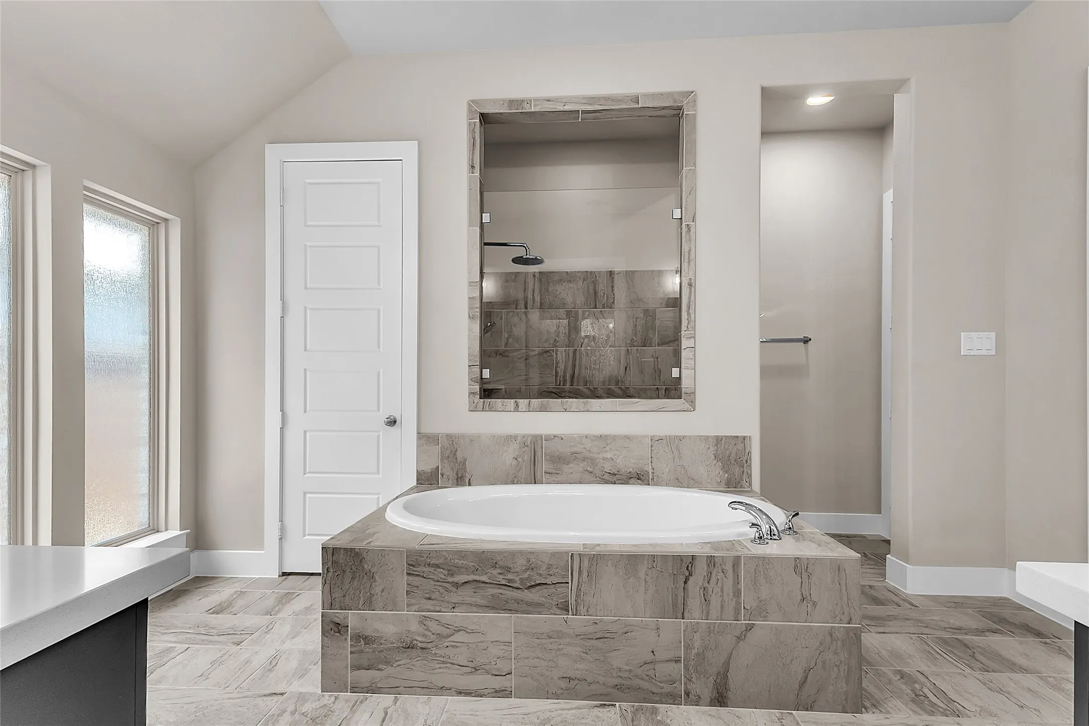 Master bathroom with a freestanding soaking tub, porcelain tile, recessed lighting, and large windows for ample natural light.