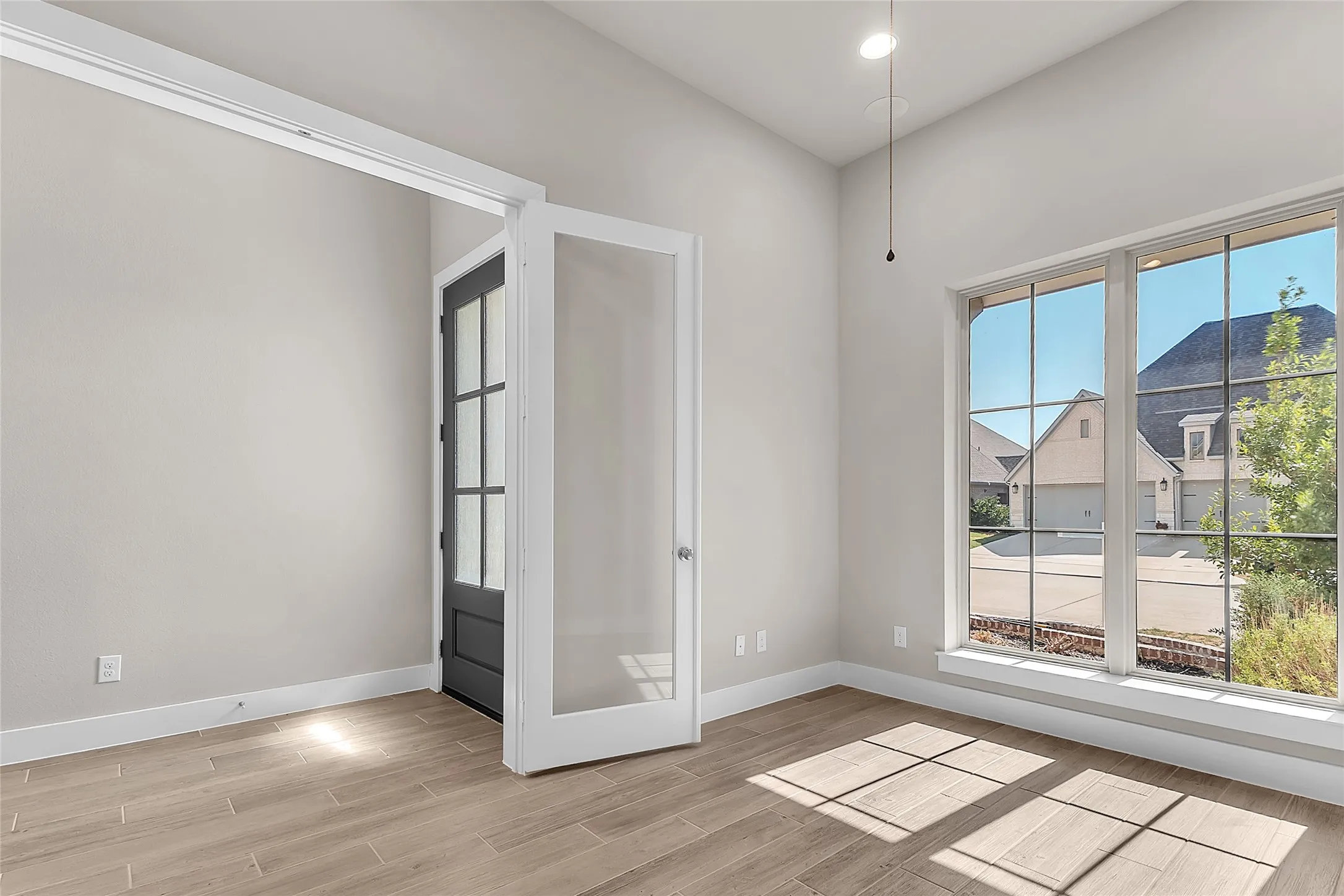Entryway with hardwood flooring, large windows, and a modern double door that provides natural light and a view of the exterior landscaping.