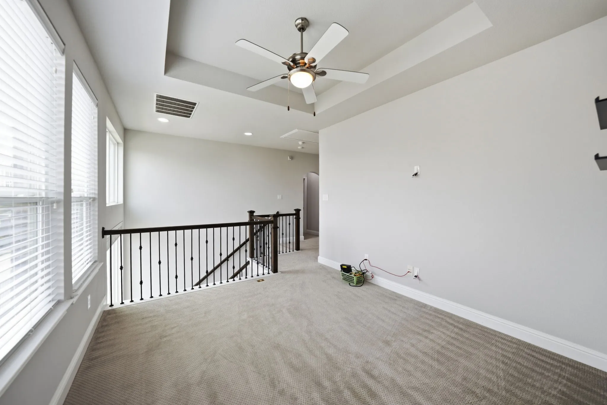 Carpeted loft area featuring a tray ceiling, recessed lighting, and a ceiling fan