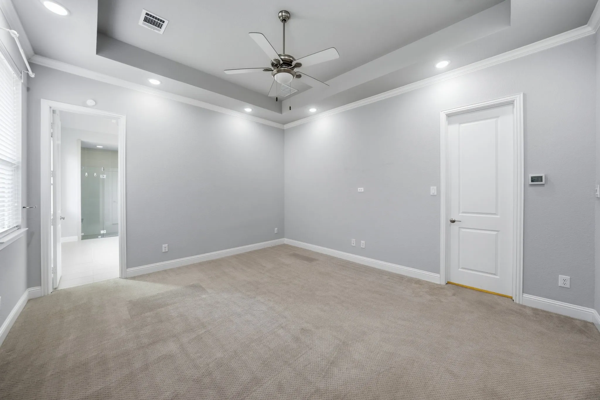 Tray ceiling with recessed lighting, ceiling fan, carpeted flooring, and crown molding
