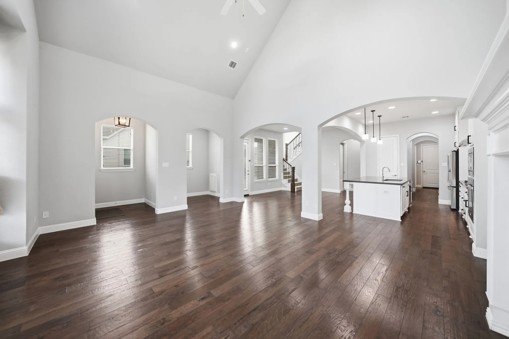 Vaulted ceiling with a ceiling fan, dark wood-finish flooring, recessed lighting, and arched doorways