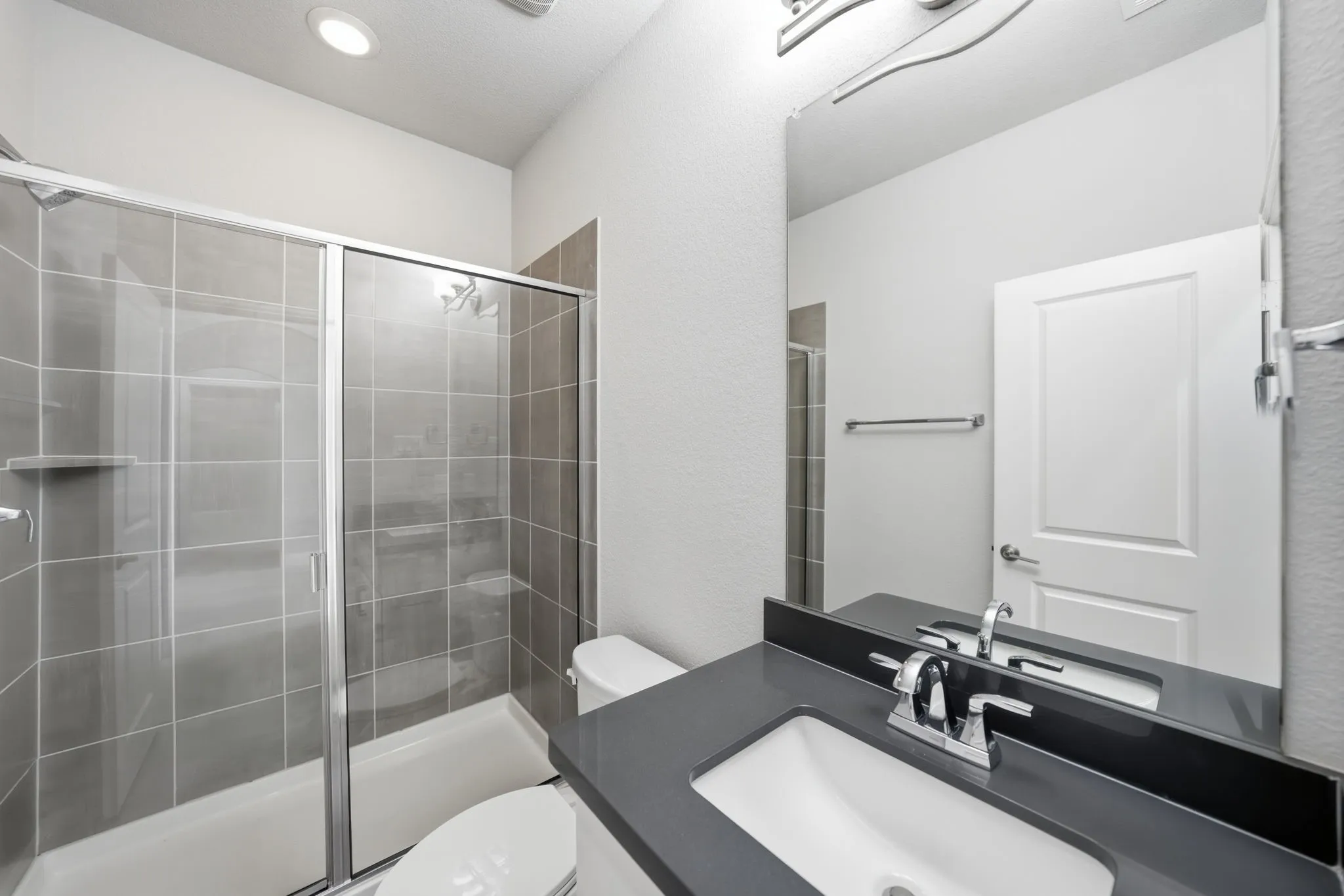 Walk-in shower with gray tile surround and glass enclosure
