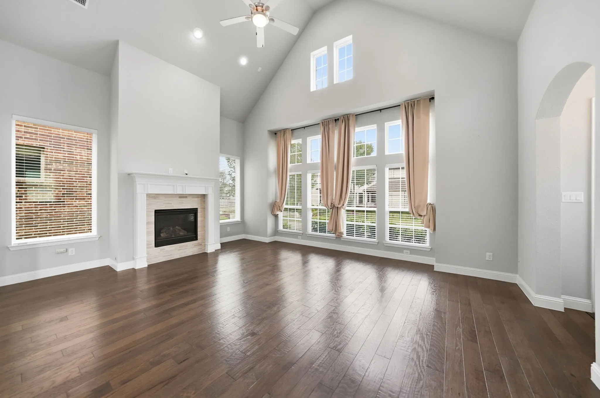 Vaulted ceiling, wood-finish flooring, fireplace with stone surround, recessed lighting, and an arched​​‌​​​​‌​​‌‌​‌‌​​​‌‌​‌​‌​‌​​​‌​​ entryway