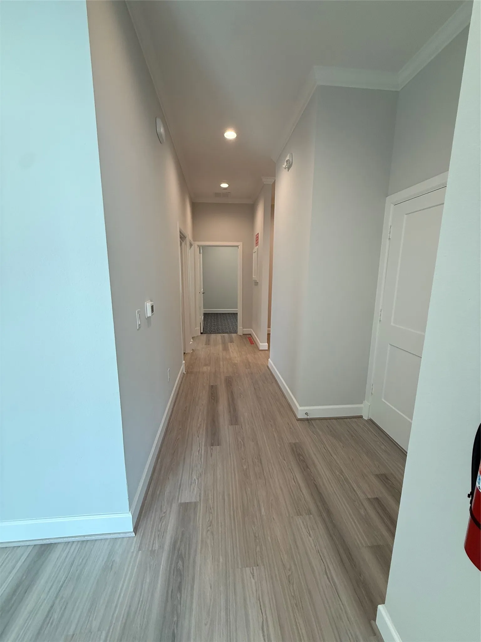 Hallway with wood-finish flooring, recessed lighting, and crown molding