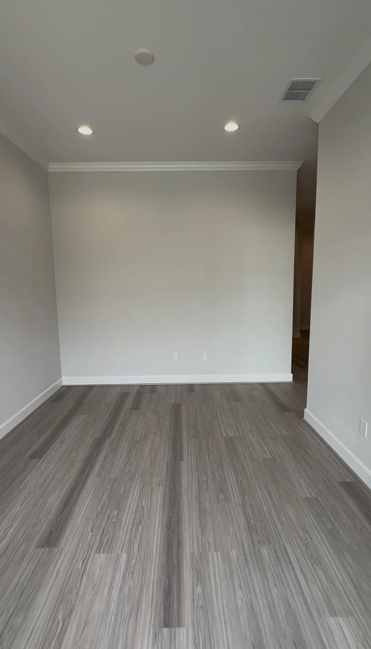 Recessed lighting, crown molding, gray wood-finish flooring, and white trim