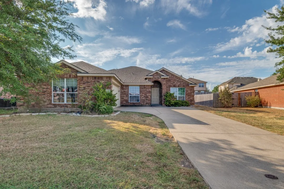 Brick exterior with an arched entryway, gabled roofline, and attached garage