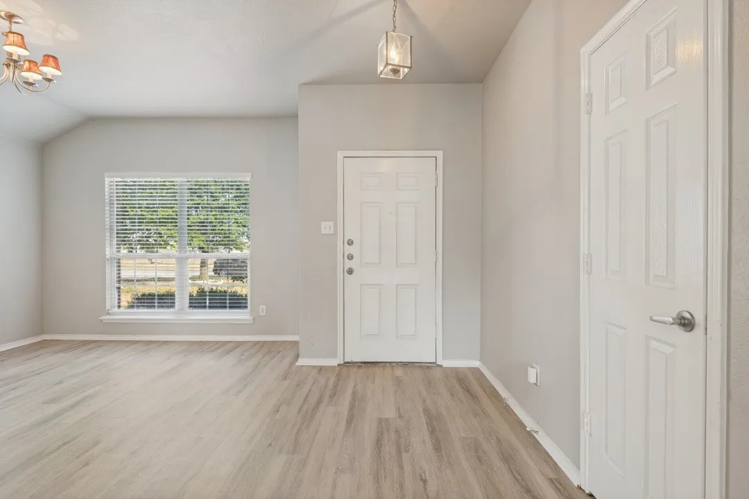 Wood-finish flooring, vaulted ceiling, and a large window with blinds