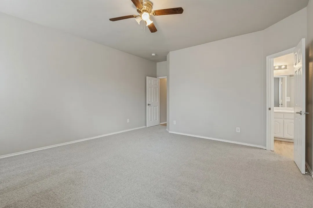 Recessed lighting, ceiling fan with light fixture, light gray carpet flooring, white interior doors, and a bathroom featuring a vanity with white cabinetry