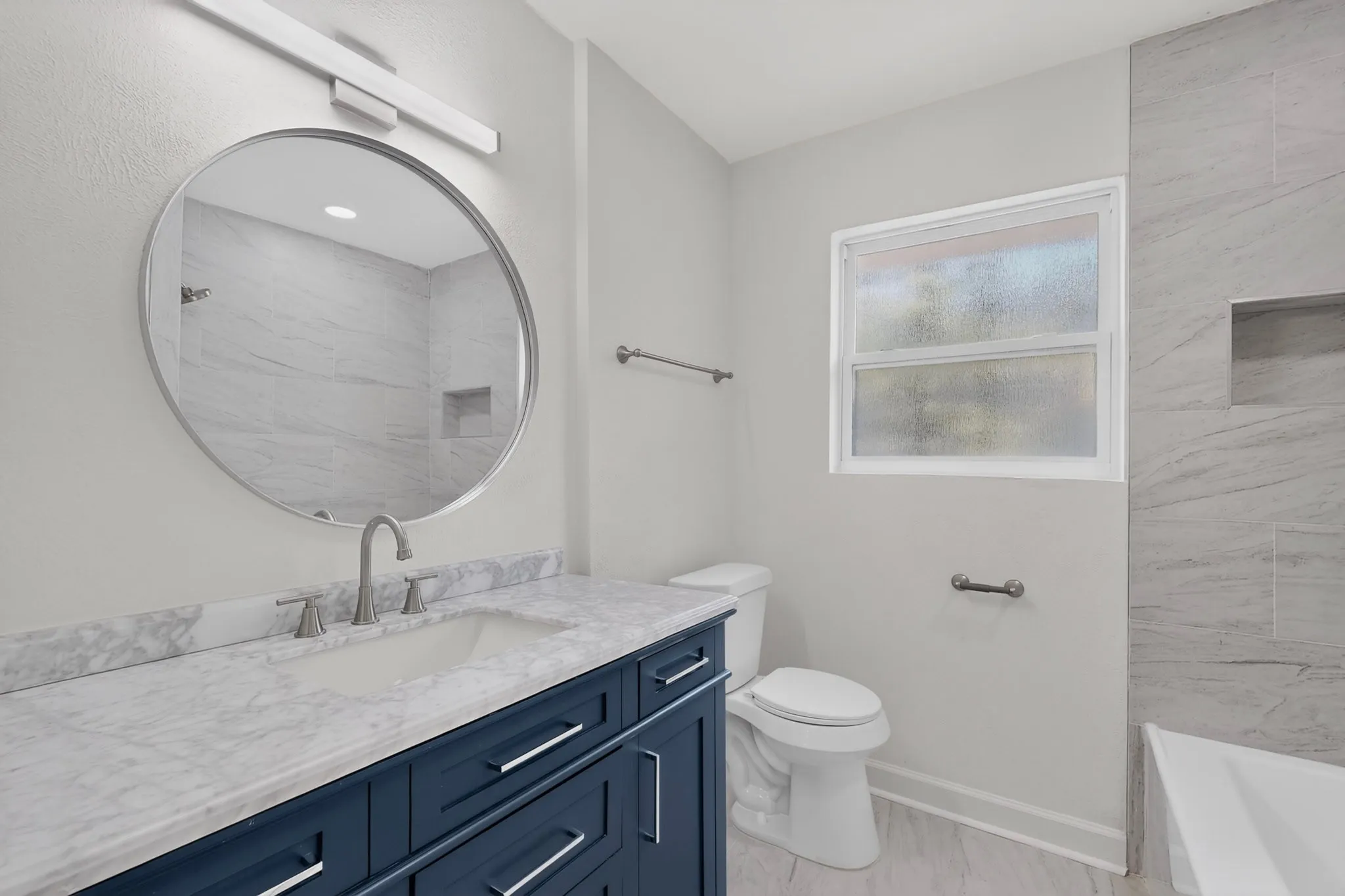 Navy blue vanity with brushed nickel hardware and a white rectangular sink