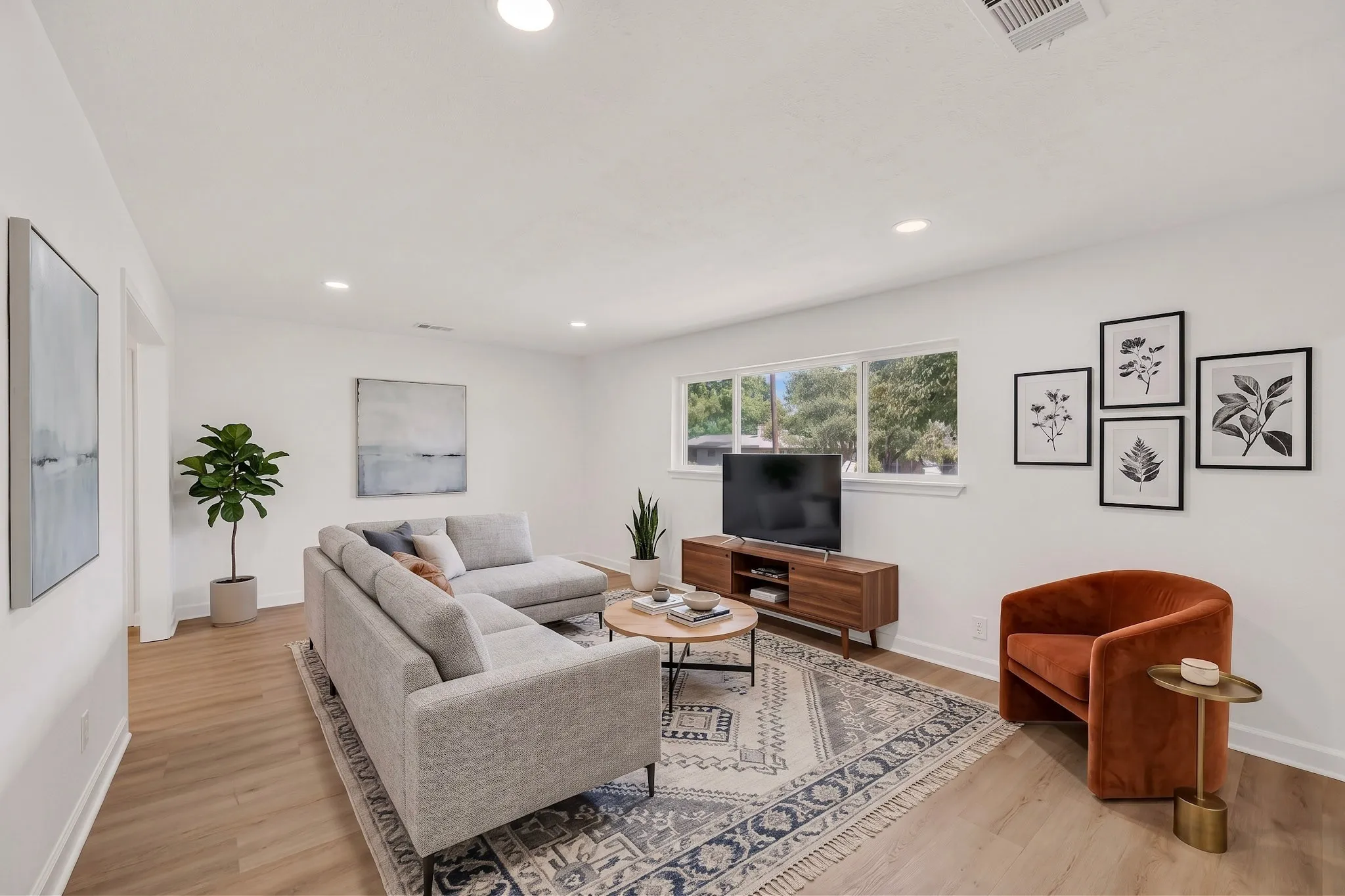Recessed lighting, light wood-finish flooring, multiple windows, white wall finishes, and a built-in media console