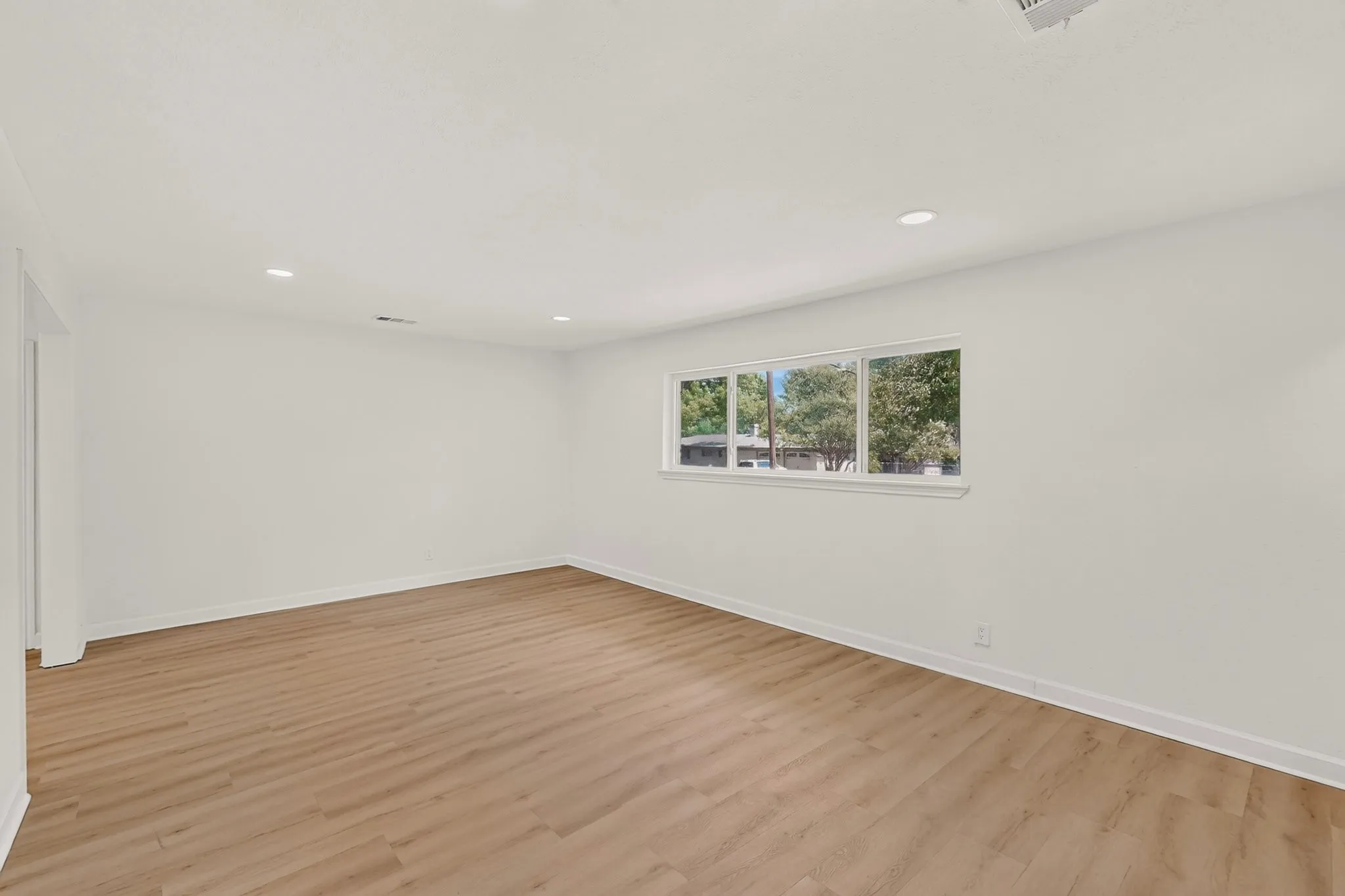 Light wood-finish flooring with white walls and recessed ceiling lighting