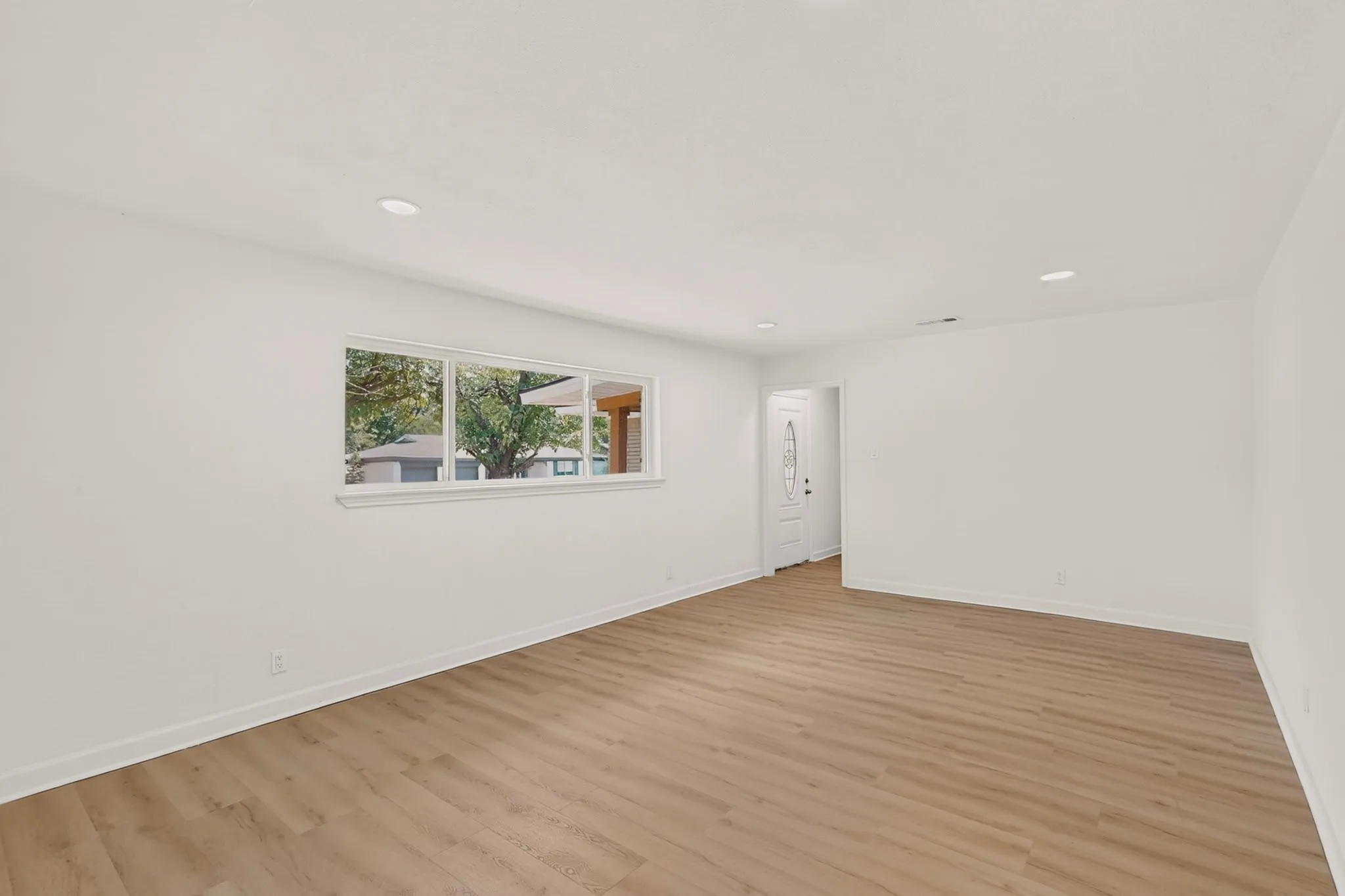 Recessed lighting, wood-finish flooring, and white interior walls