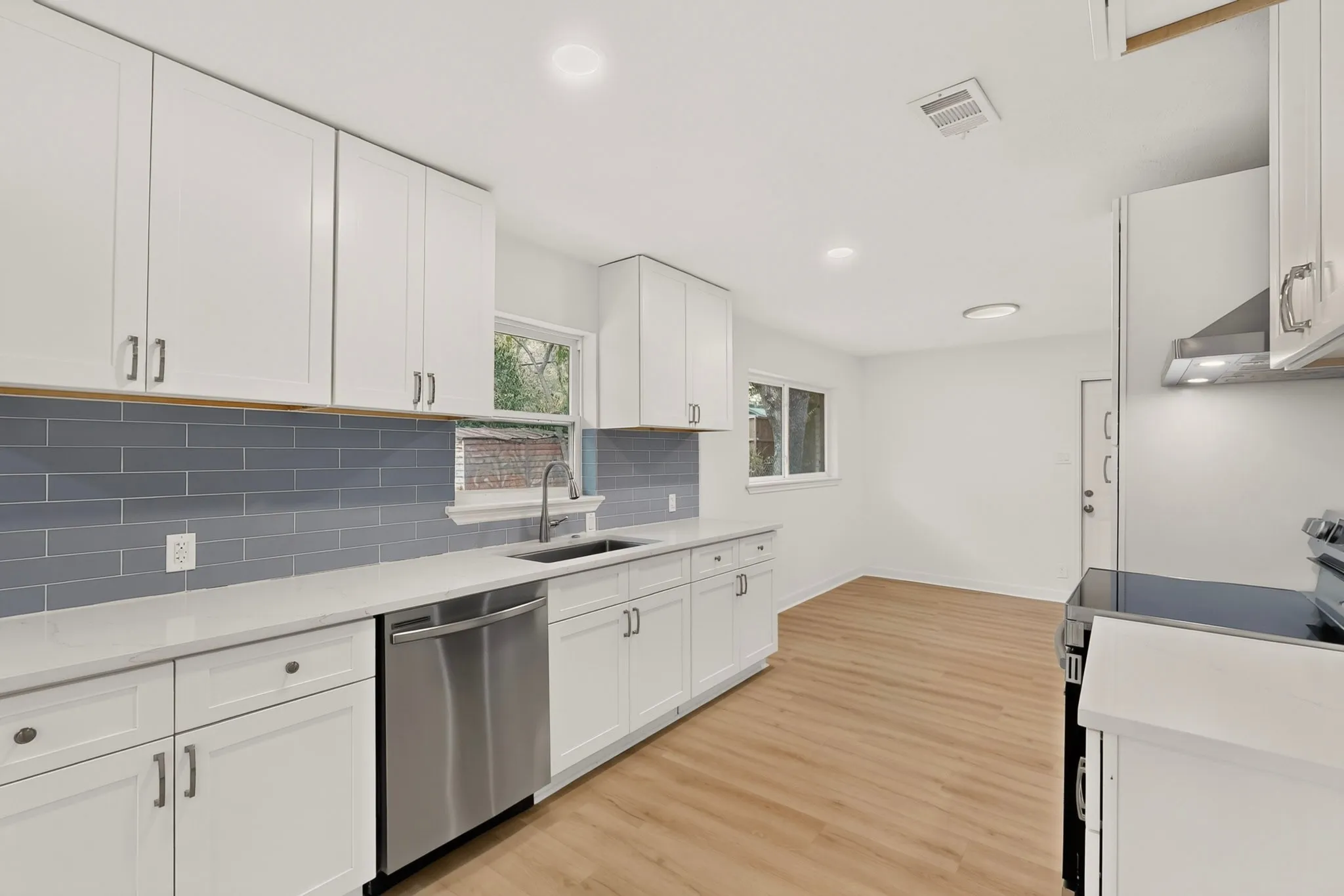 Kitchen featuring white cabinetry, subway tile backsplash, stainless steel appliances, and wood-finish flooring