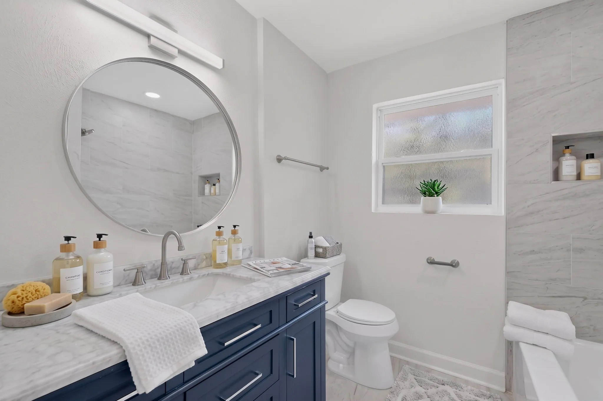Deep blue vanity with a marble countertop, undermount sink, and brushed nickel fixtures