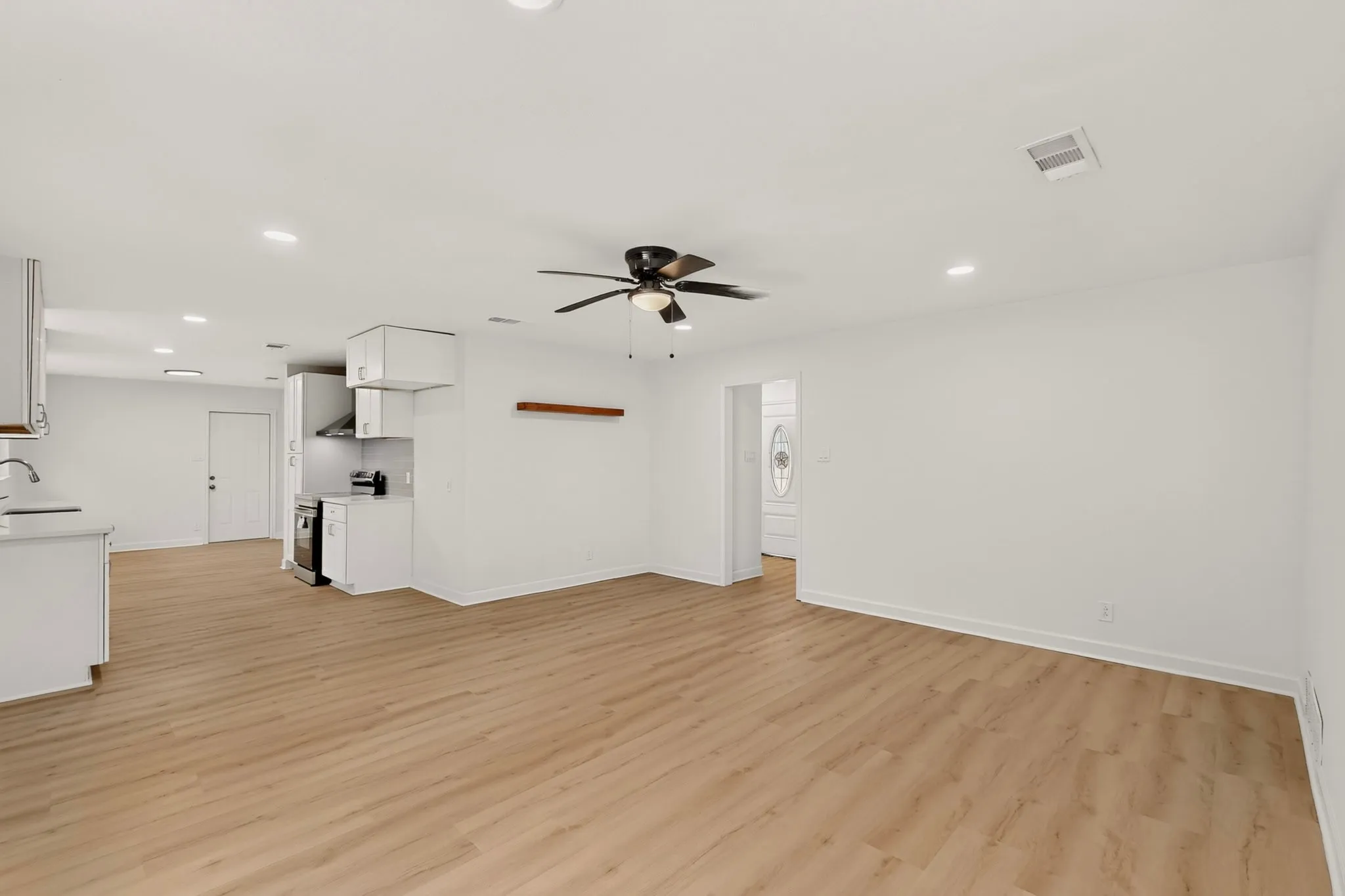 Open-concept layout with wood-finish flooring, recessed lighting, and a ceiling fan