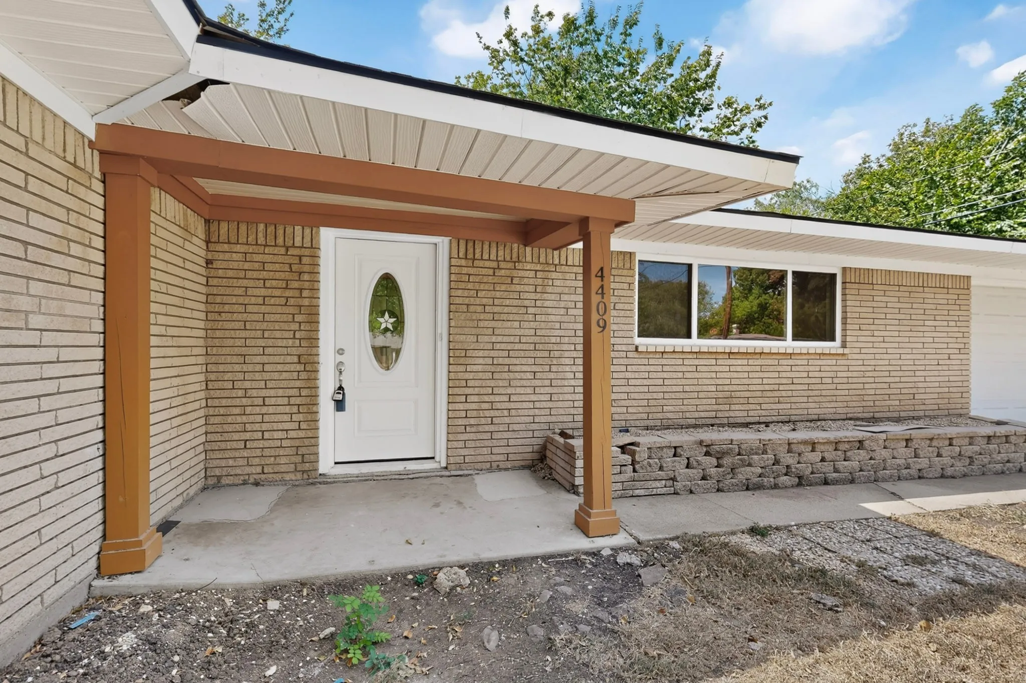 Brick exterior with a covered porch featuring wood-tone support columns