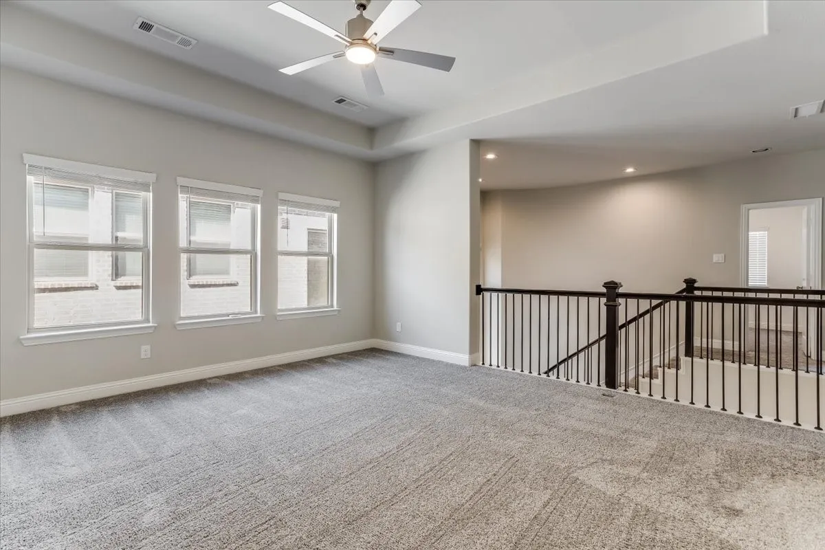 Spacious room with gray carpet flooring, multiple windows, a ceiling fan, and recessed lighting
