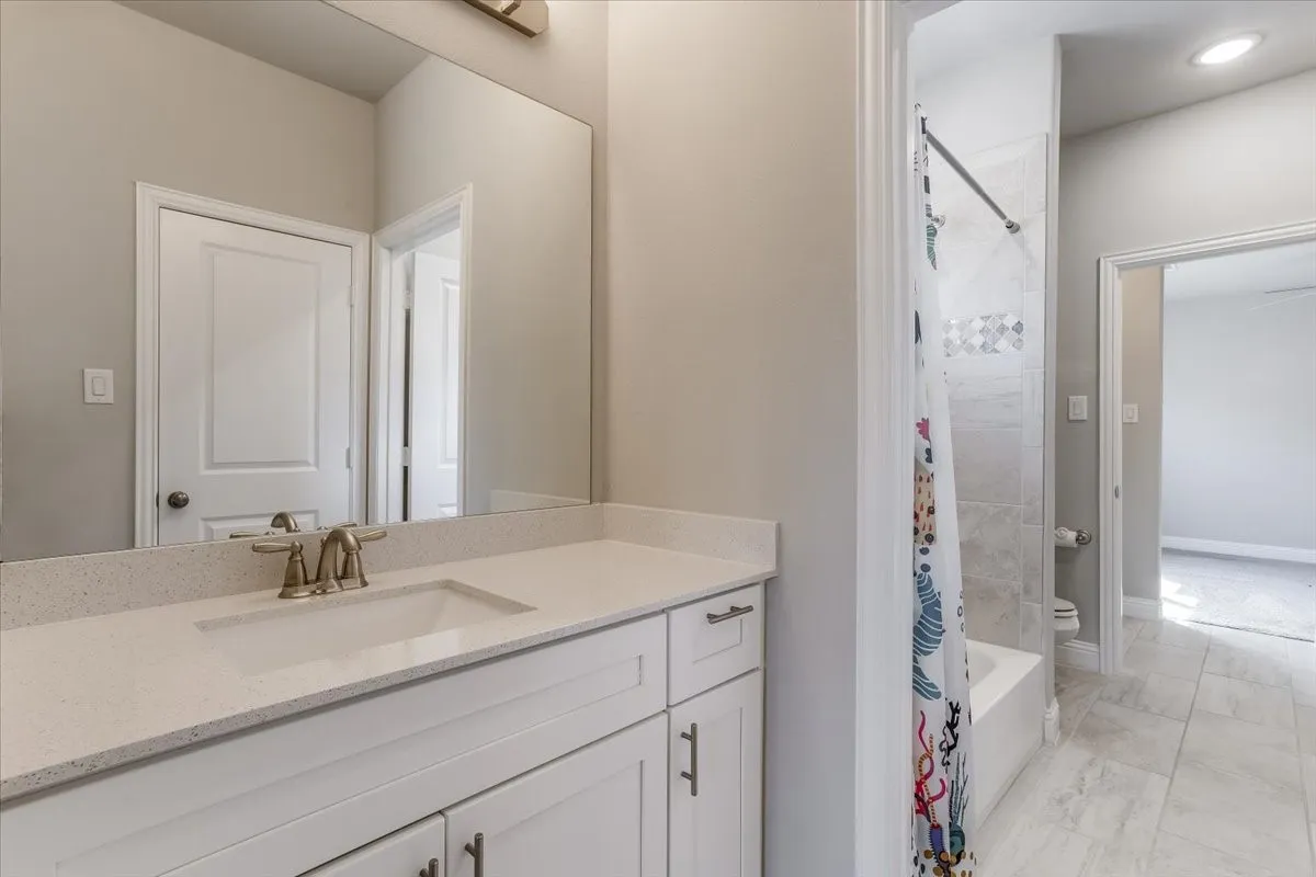 White vanity with integrated sink, light-colored countertop, and brushed nickel faucet