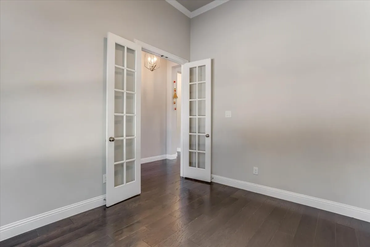 French doors with glass panels, wood-finish flooring, light gray wall tones, and crown molding