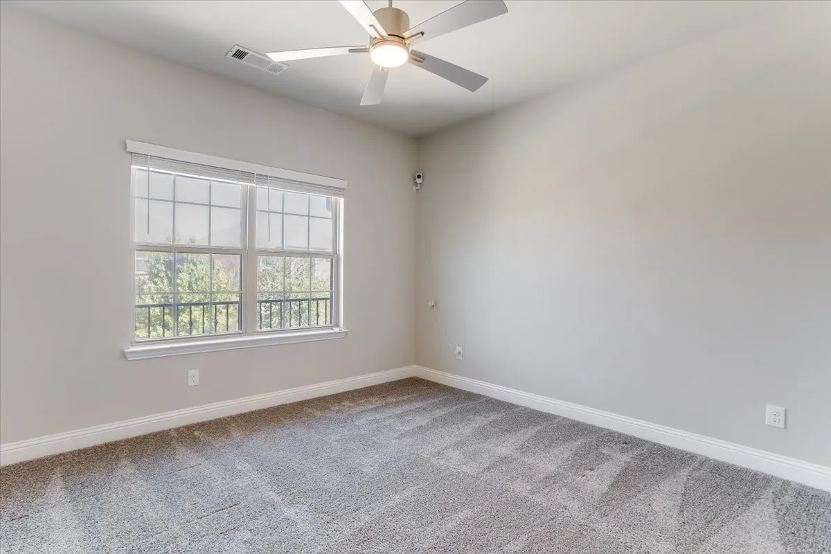Wall-to-wall carpeting, dual windows with blinds, ceiling fan with integrated lighting, and neutral wall tones