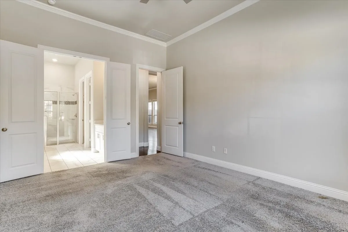 Neutral wall tones, crown molding, gray carpet flooring, white trim, and white paneled doors