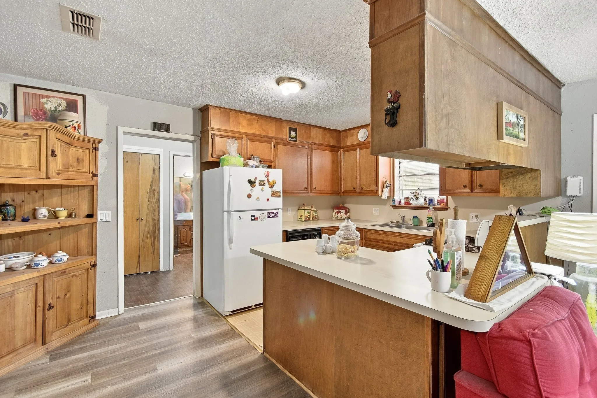 Kitchen featuring wood cabinetry, a built-in breakfast bar, and wood-finish flooring