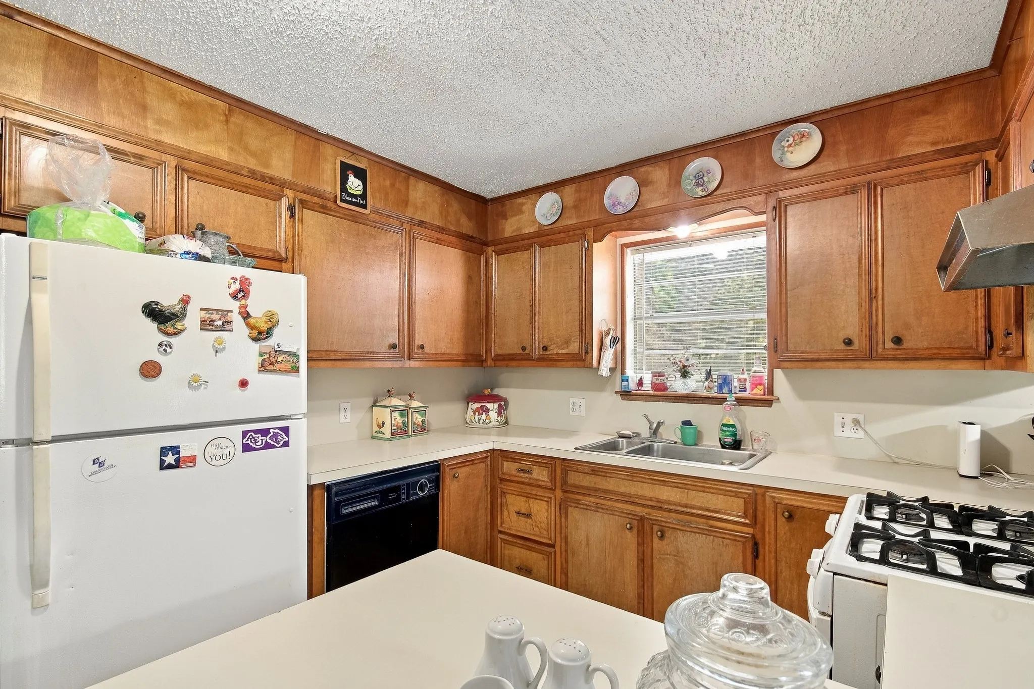 Wood paneling throughout, built-in cabinetry, white countertops, stainless steel double basin sink, and a four-burner gas range