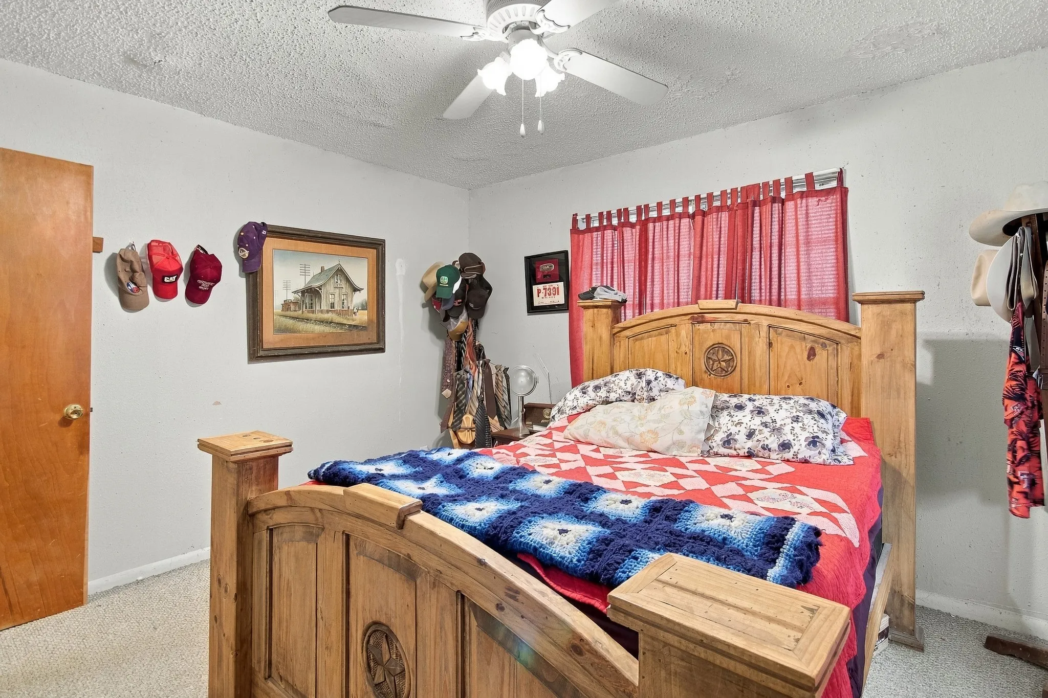 Carpeted flooring, light-colored walls, wood-tone door, and a ceiling fan with integrated lighting