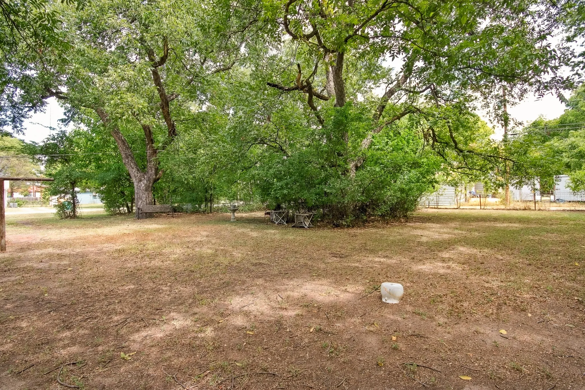 Expansive outdoor space featuring mature trees and a partial fence line