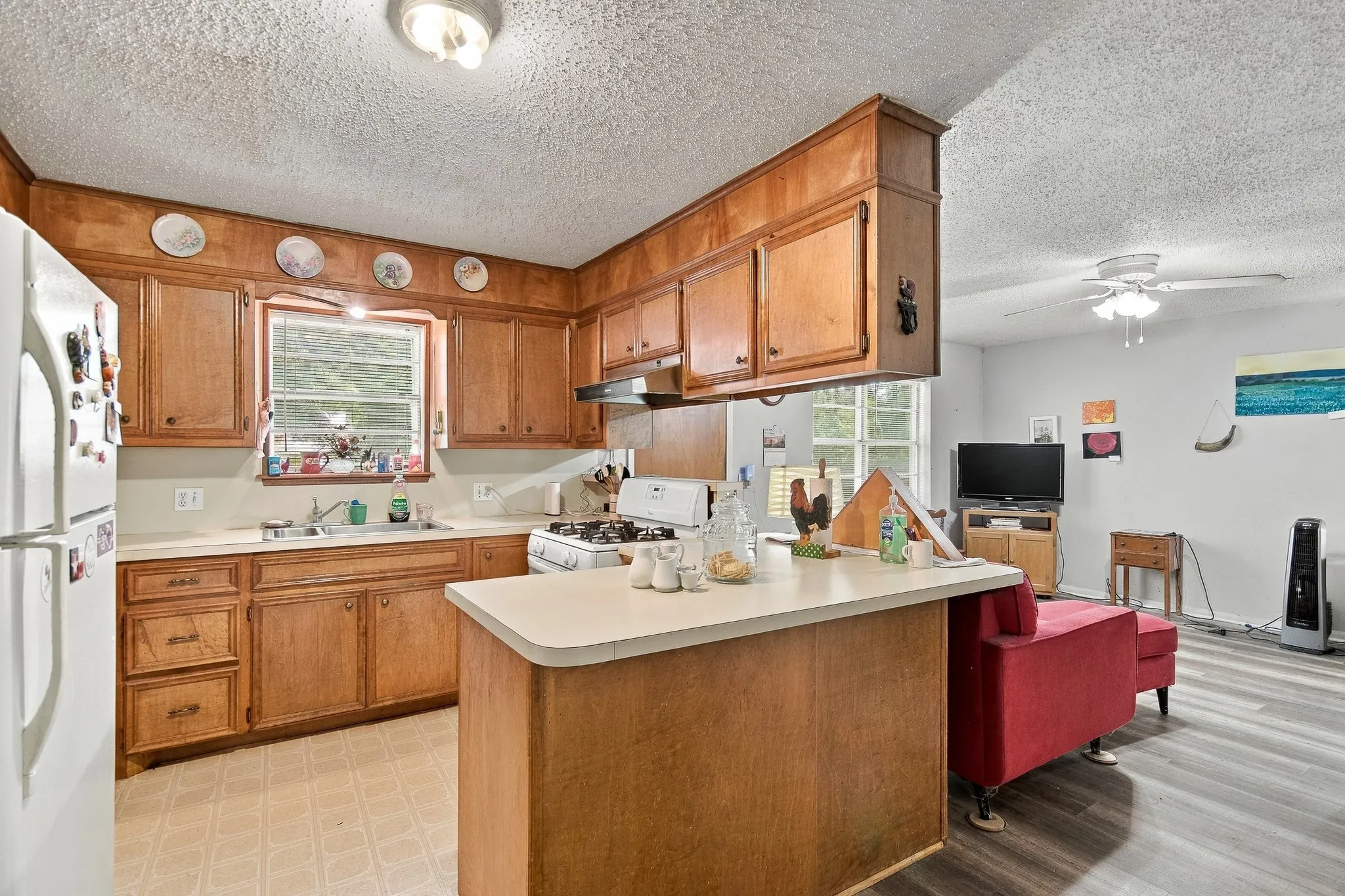 Wood-finish cabinetry, light-toned countertops, a built-in kitchen island, and a sink with a window above